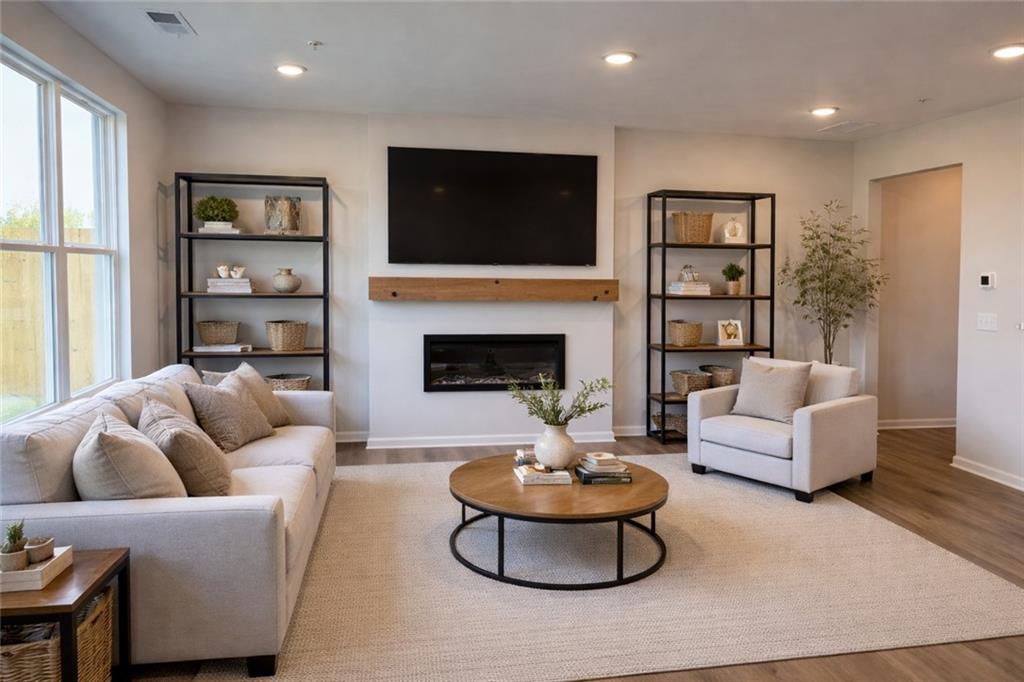Cozy living room with gas fireplace, mounted TV, beige sofa, bookshelves and plants in Davidson Homes The Wake E, Cumming, Georgia