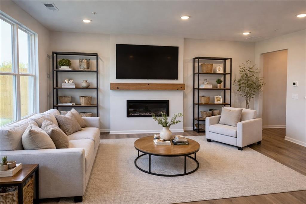 Cozy living room with gas fireplace, mounted TV, beige sofa, bookshelves and plants in Davidson Homes The Wake E, Cumming, Georgia