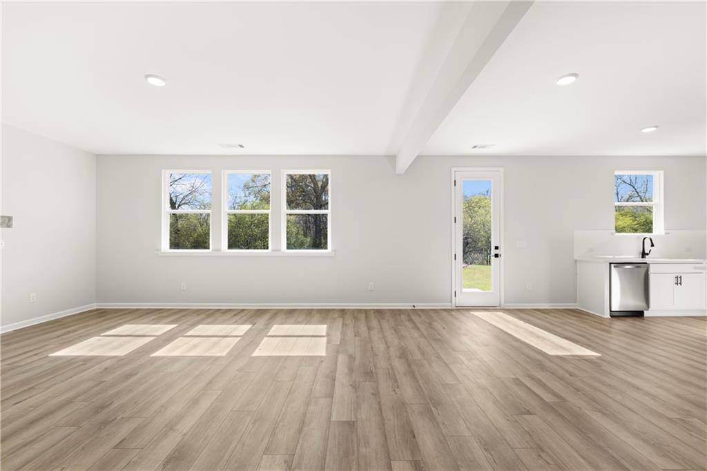 Spacious empty great room with hardwood floors, large windows, French doors to backyard, and wet bar in 5-bedroom Davidson Homes The Hickory B, Winder, GA