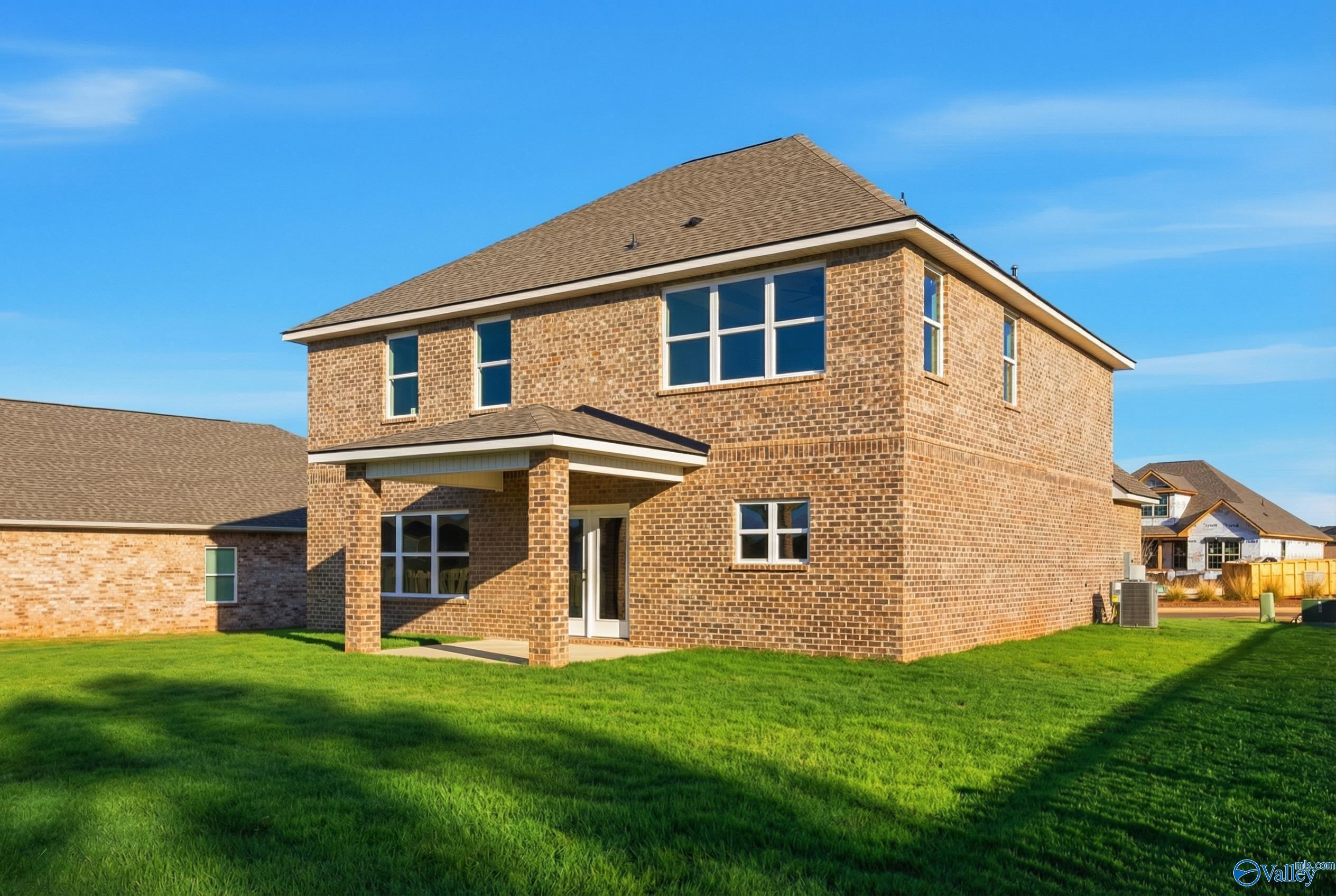 Two-story brick exterior with 2-car garage, covered porch, and lush green lawn in Creekside, Harvest, Alabama Davidson Homes Chelsea C