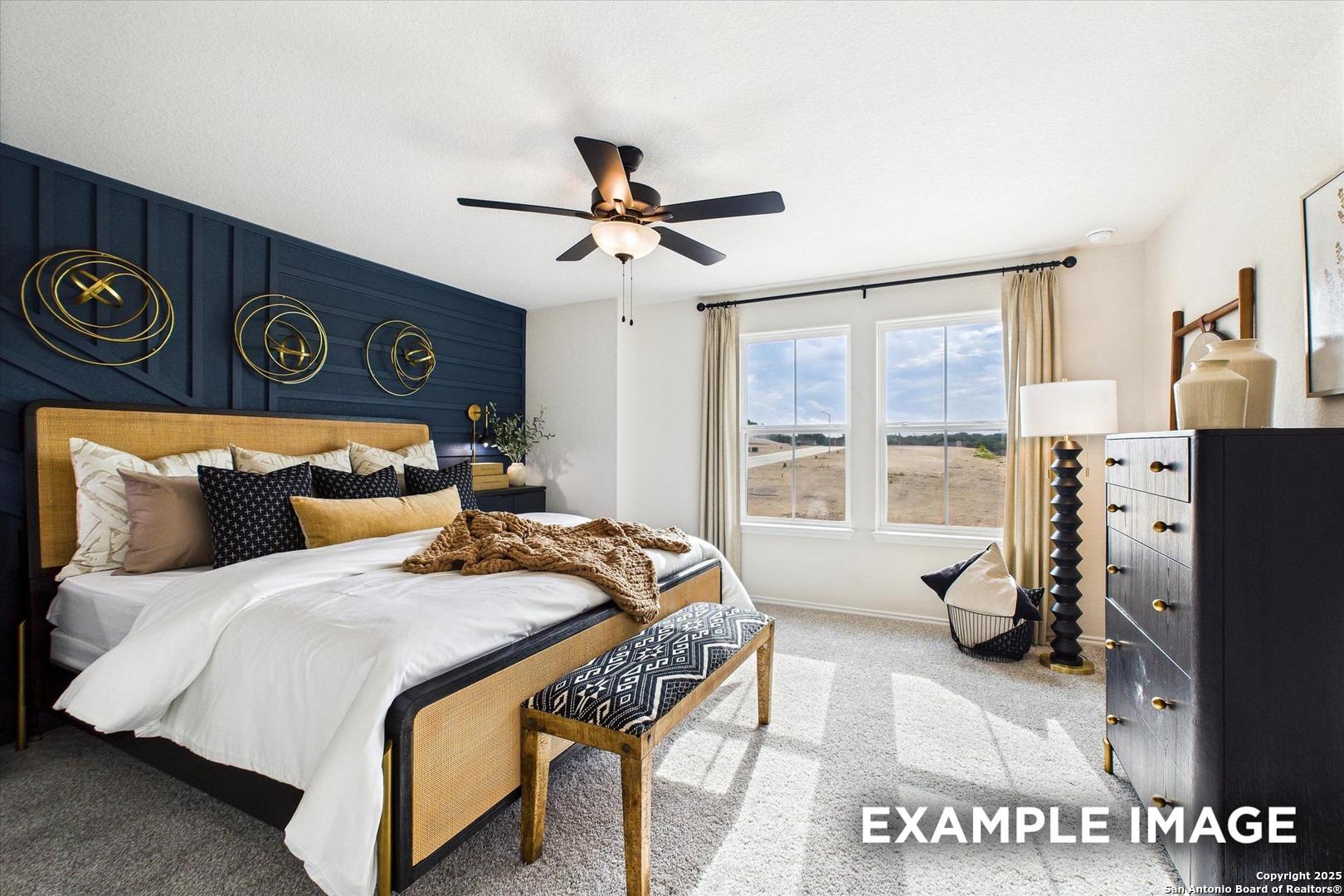 Elegant master bedroom with navy accent wall, gold decor, king bed, ceiling fan in Davidson Homes The Florence C, San Antonio