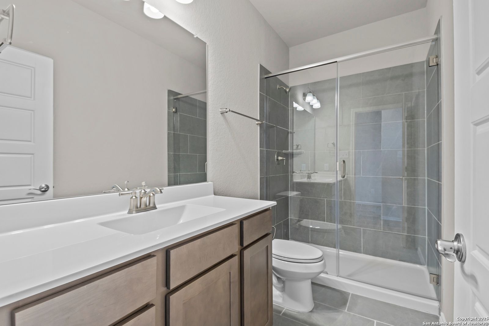 Modern bathroom with double vanity, frameless glass shower, subway tile, and neutral tones in Davidson Homes The Collin B, Seguin, Texas