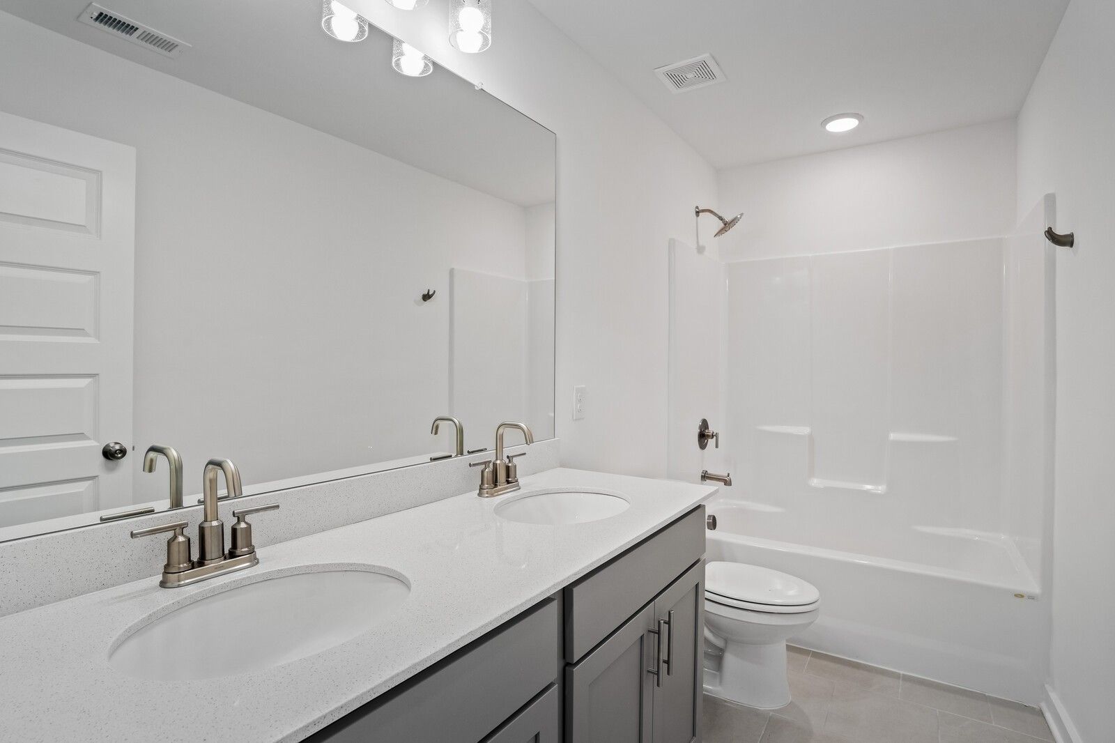 Modern bathroom with dual vanity, quartz countertops, and tub-shower combo in The Logan C home at Calista Farms, Tennessee.