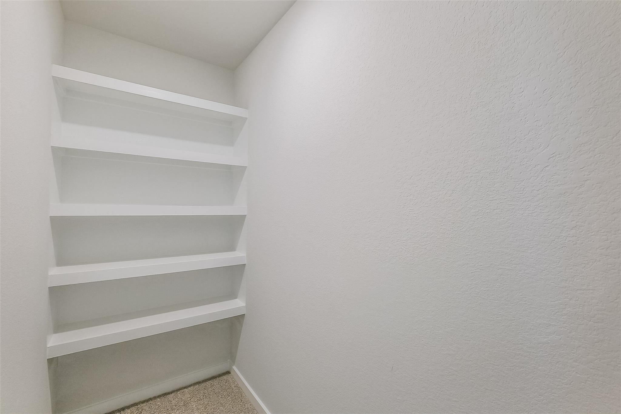 Spacious walk-in closet with white built-in shelving in master suite of Davidson Homes The Tierra B, Emberly, Beasley, Texas