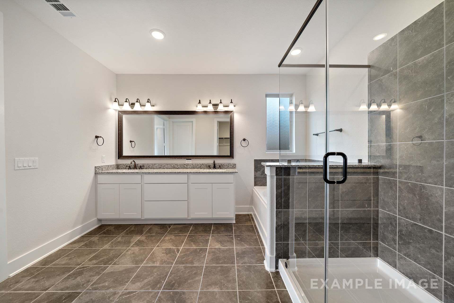 Master bathroom in The Victoria by Davidson Homes featuring dual vanity, frameless glass shower, and garden tub.
