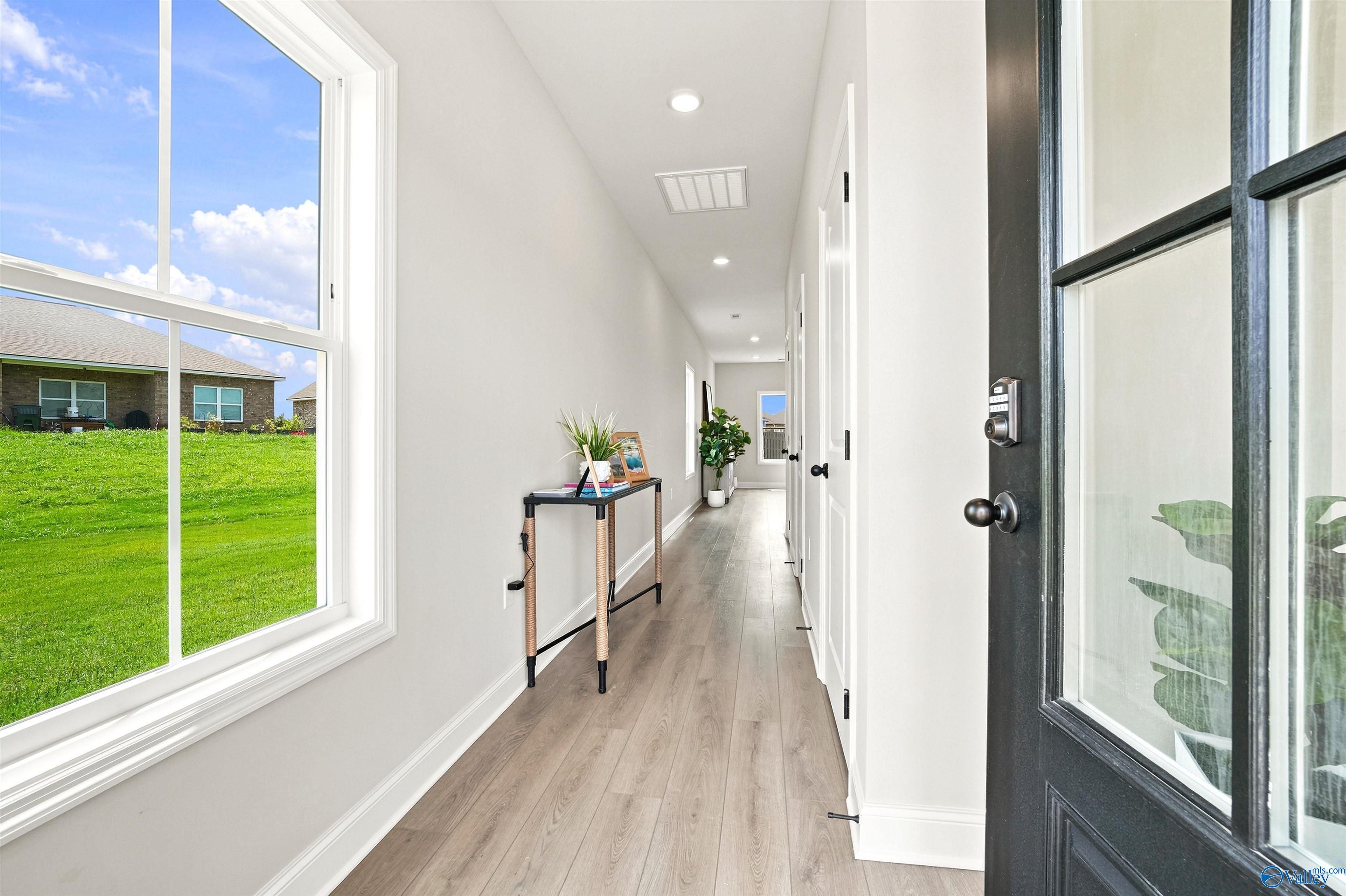 Bright, modern entryway hallway with wood-style flooring in The Burton B floor plan at Heritage Lakes, New Market, Alabama.