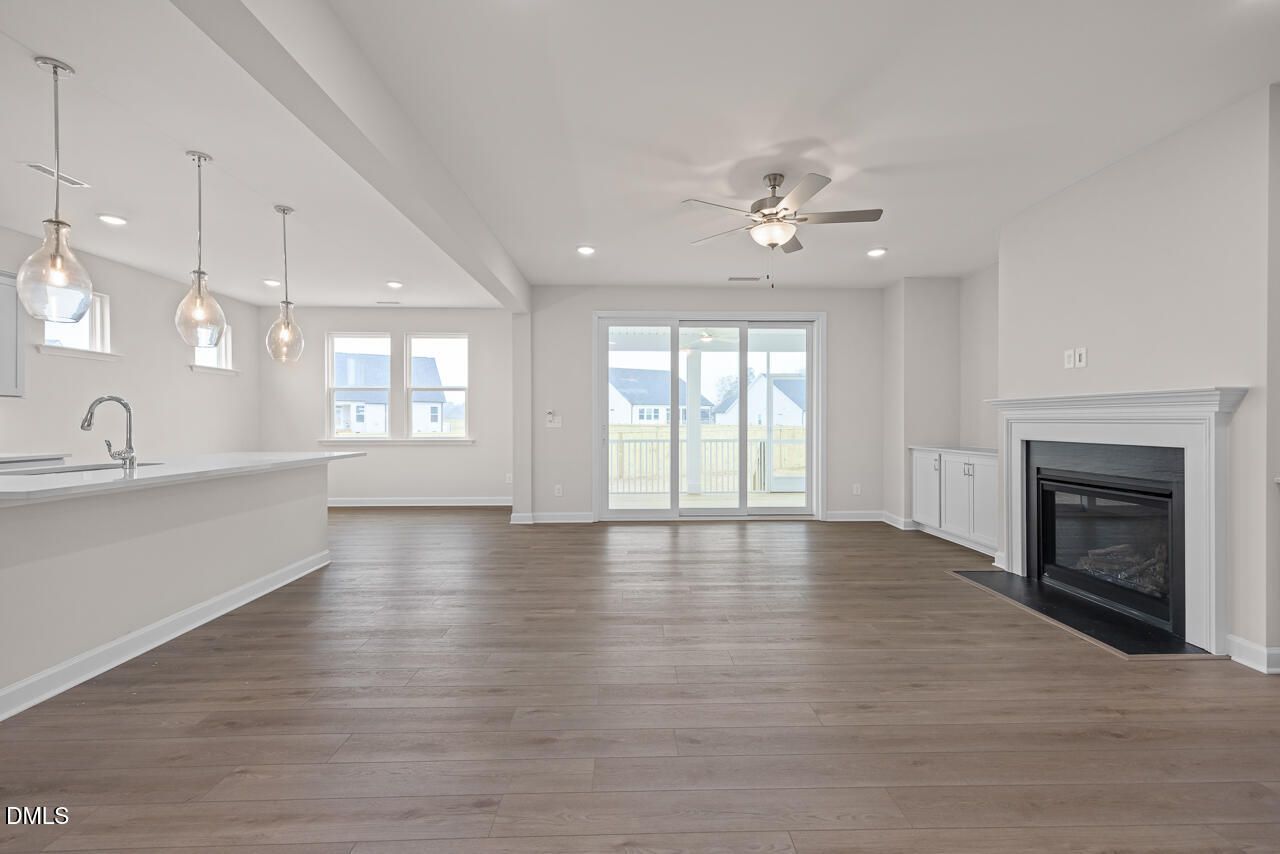 Open-concept living room with white stone fireplace, kitchen island, and sliding patio doors in Davidson Homes The Cypress D II, Angier, NC