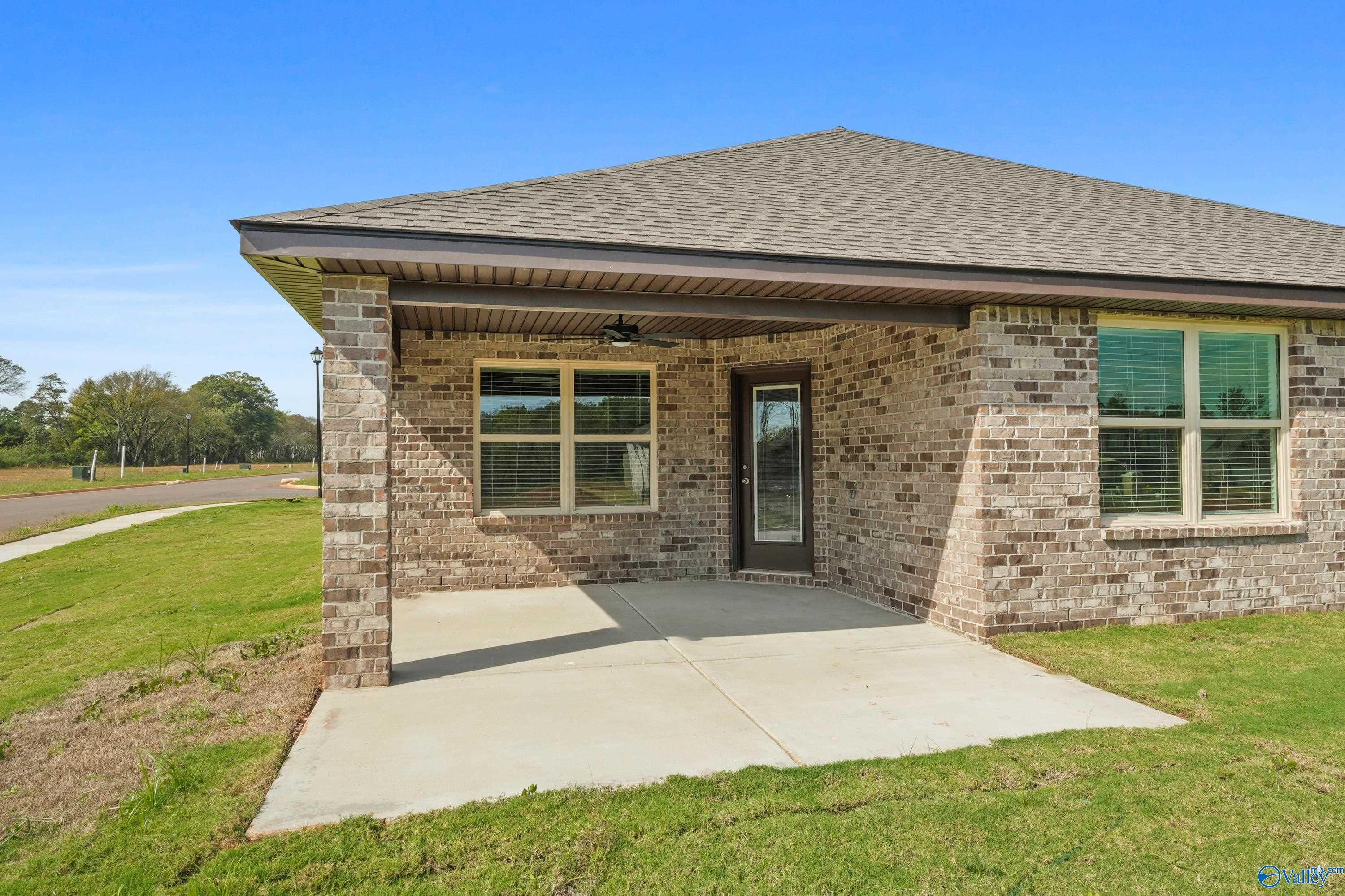 Single-story brick home exterior with covered entry porch, double windows, and lush lawn in The Meadows, Athens, Alabama