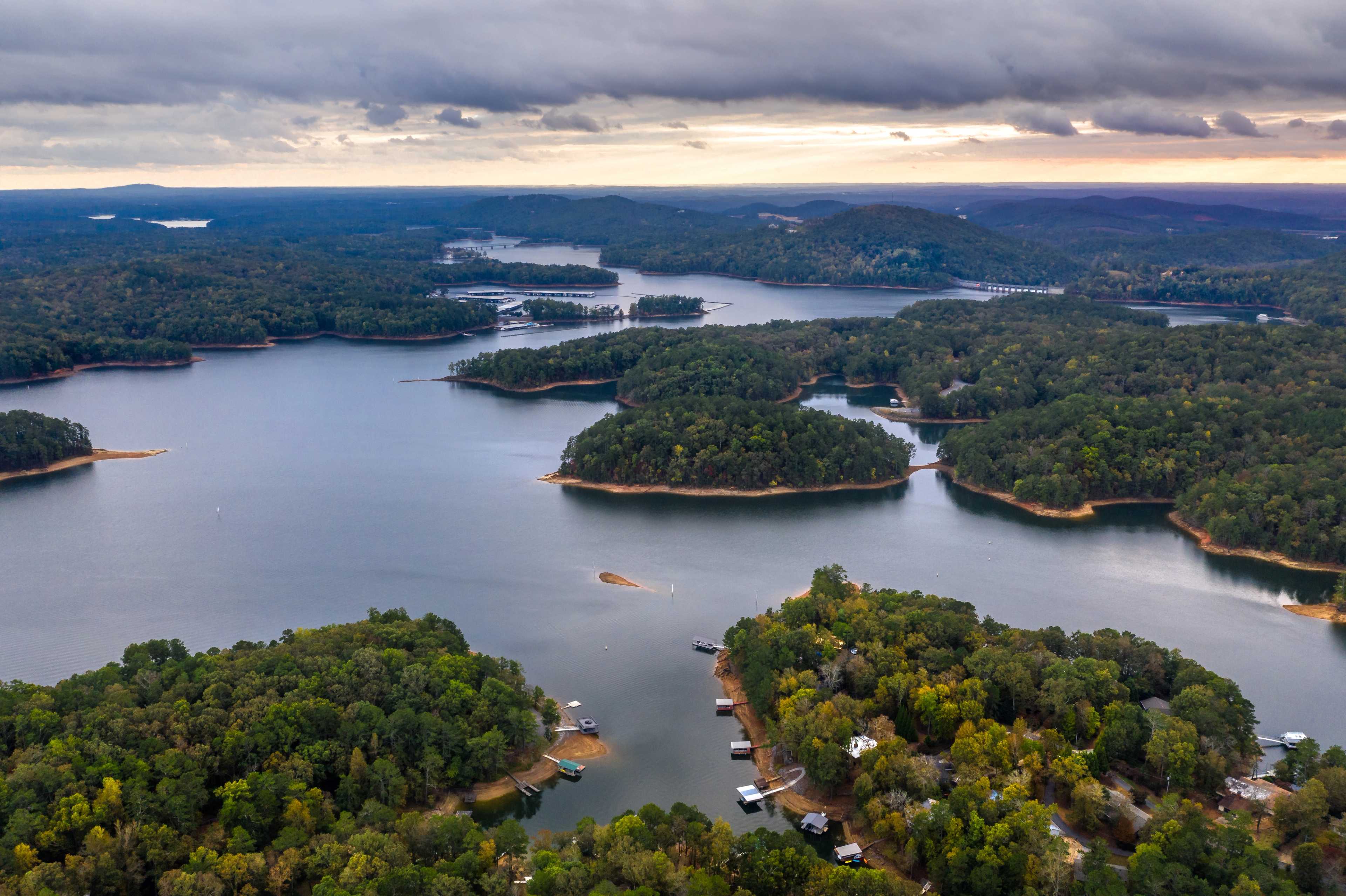 Aerial view of serene lake with forested islands, docks, and waterfront homes in Grafton Trace, Woodstock, Georgia
