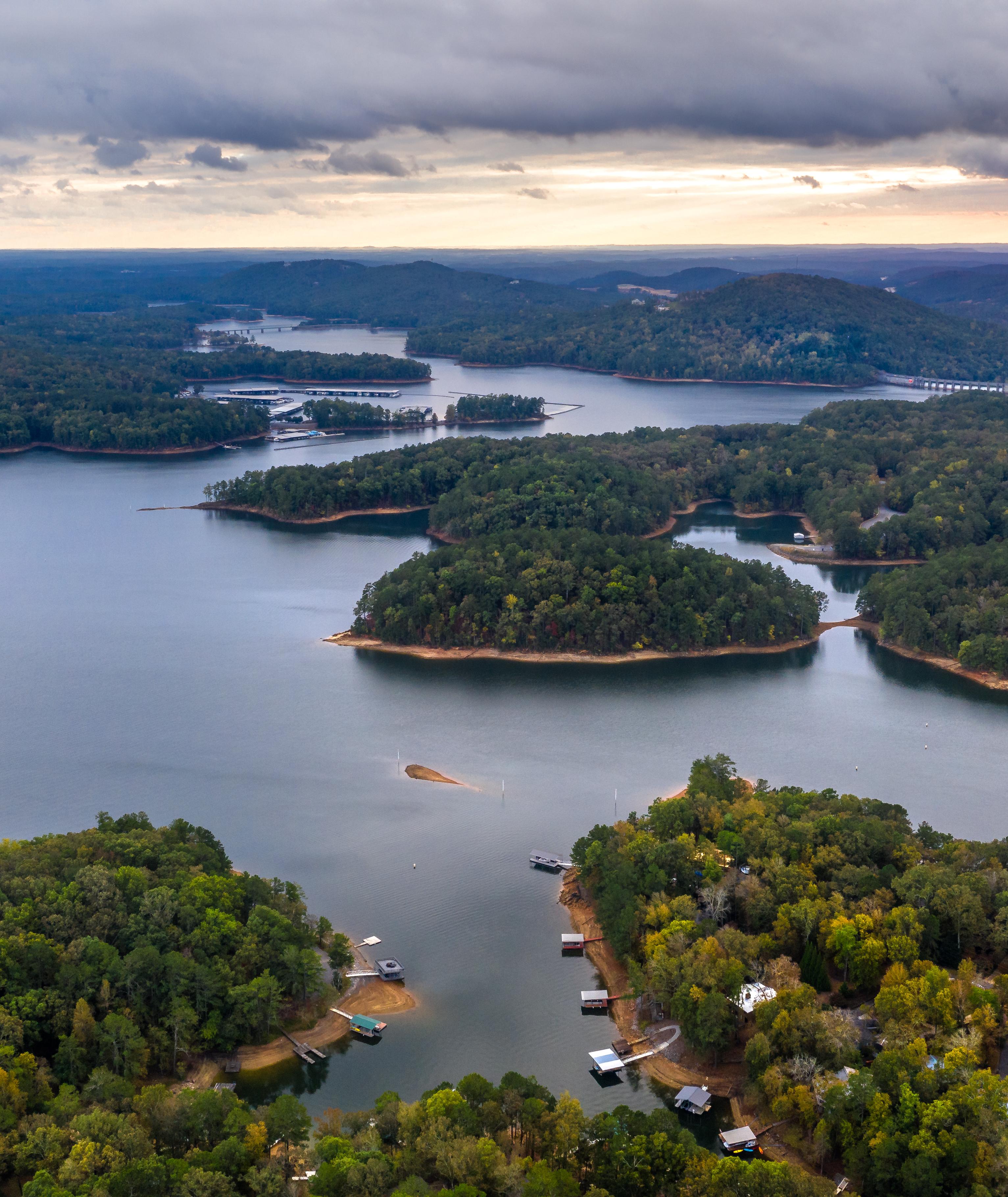 Aerial view of serene lake with forested islands, docks, and waterfront homes in Grafton Trace, Woodstock, Georgia