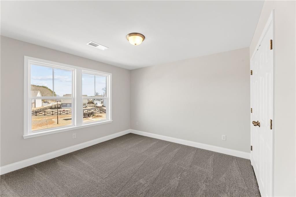 Bright bedroom with large windows overlooking rural barn view, gray carpet in The Willow B home by Davidson Homes, Hoschton, GA