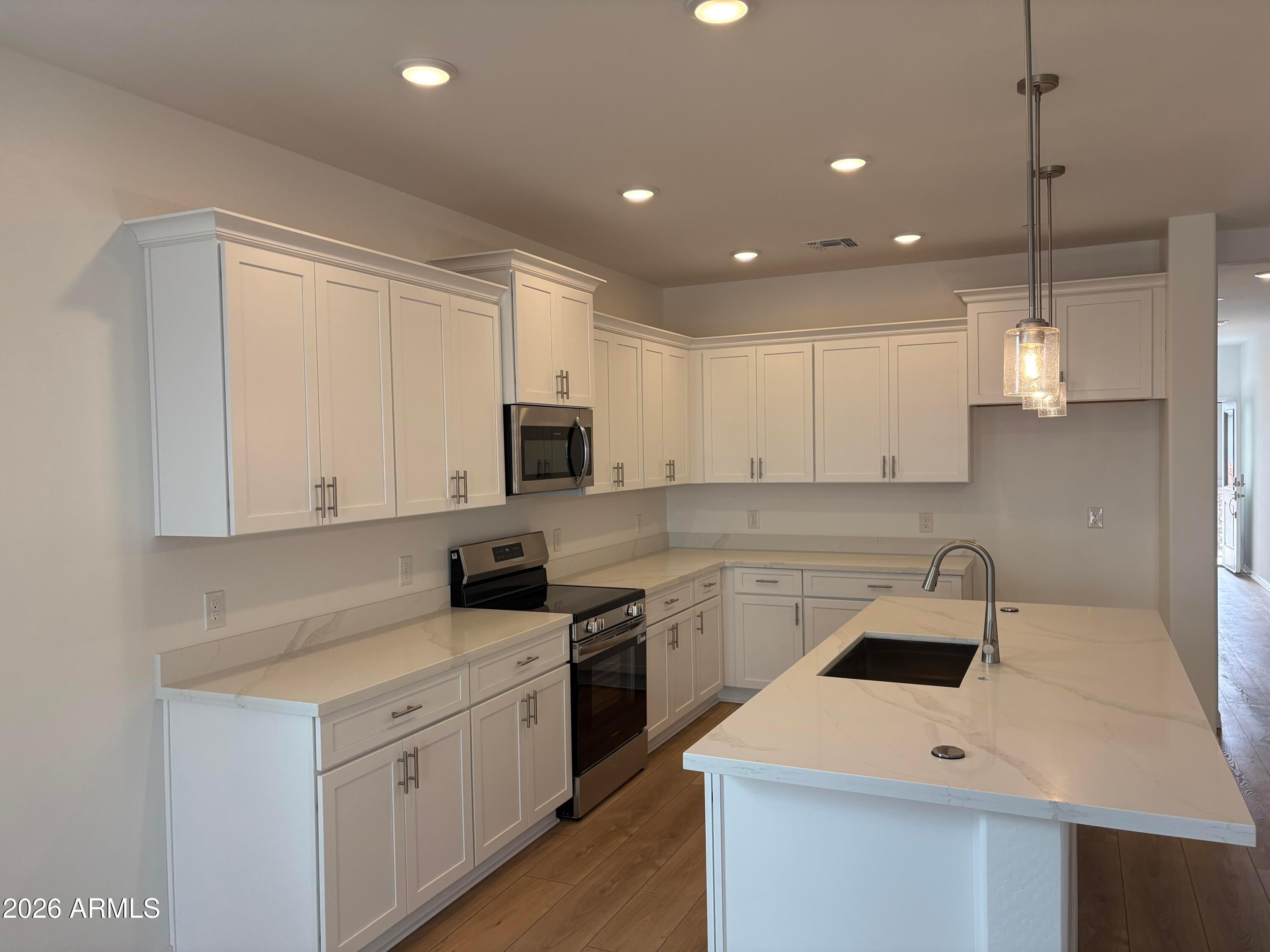 White shaker kitchen with quartz countertops, large island, and stainless appliances in Davidson Homes Evergreen B, Cottonwood AZ