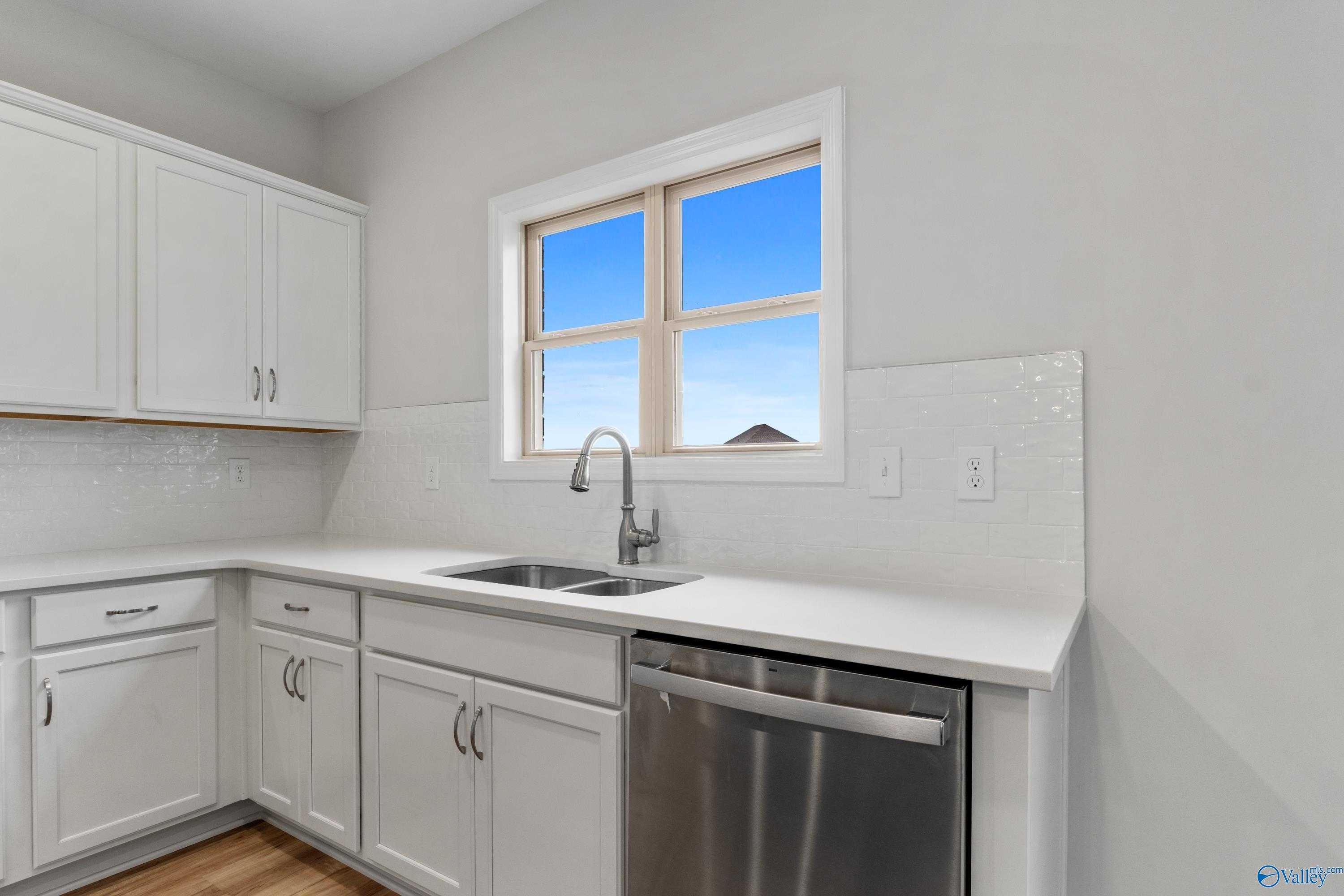 Bright kitchen with white cabinets, stainless dishwasher, subway tile backsplash, and window in Davidson Homes Chelsea C, Harvest AL