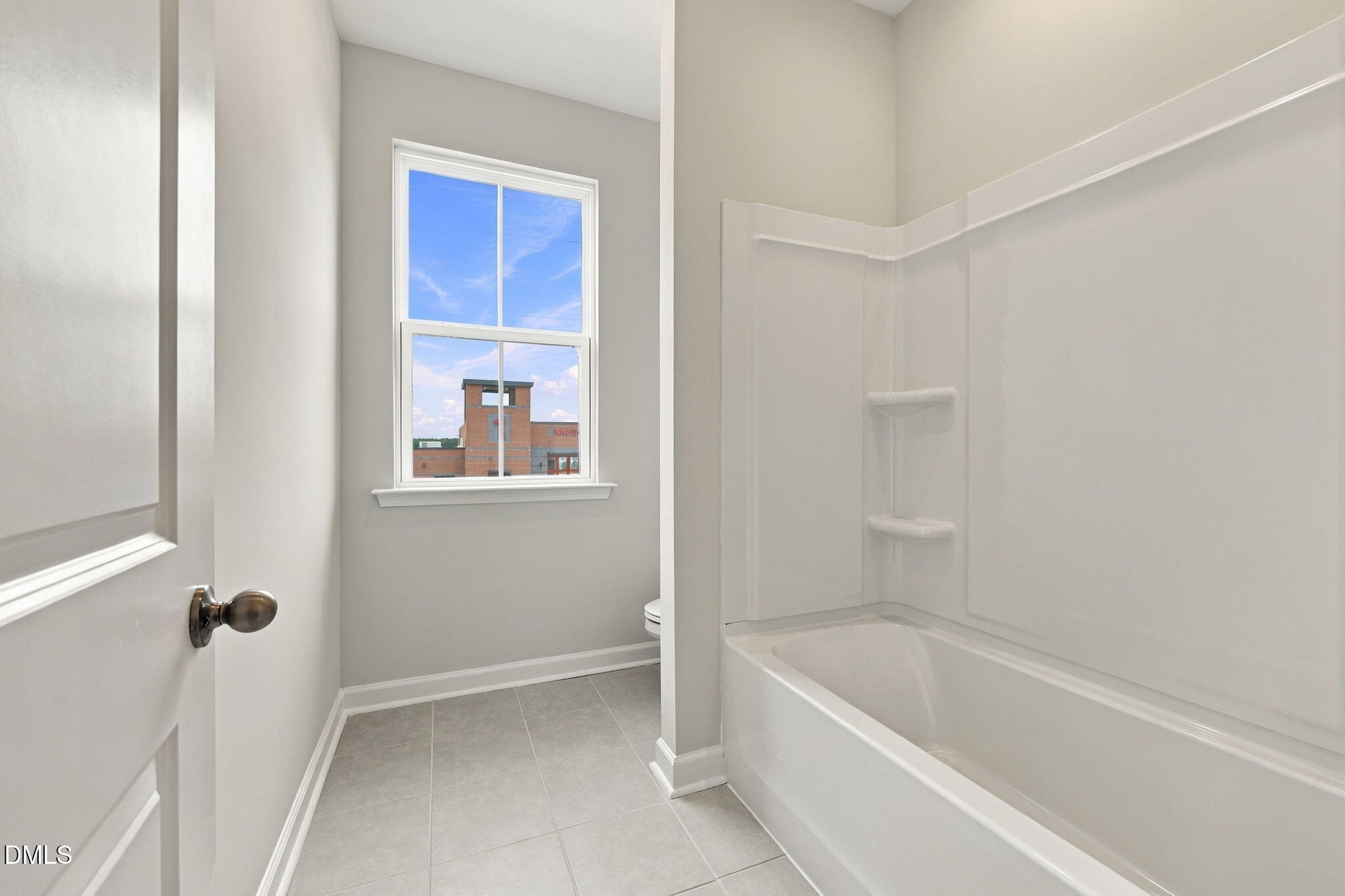 Bright white tile bathroom with tub shower combo and natural light in Davidson Homes The Alexander B, Knightdale, North Carolina