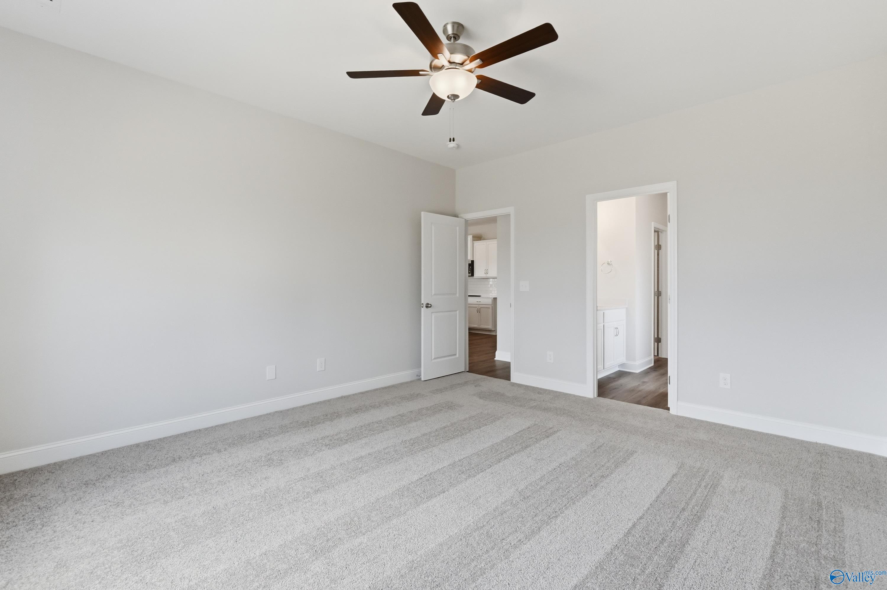 Spacious secondary bedroom with ceiling fan, beige walls, gray carpet, and adjacent bath in Davidson Homes The Daphne C, Toney, AL
