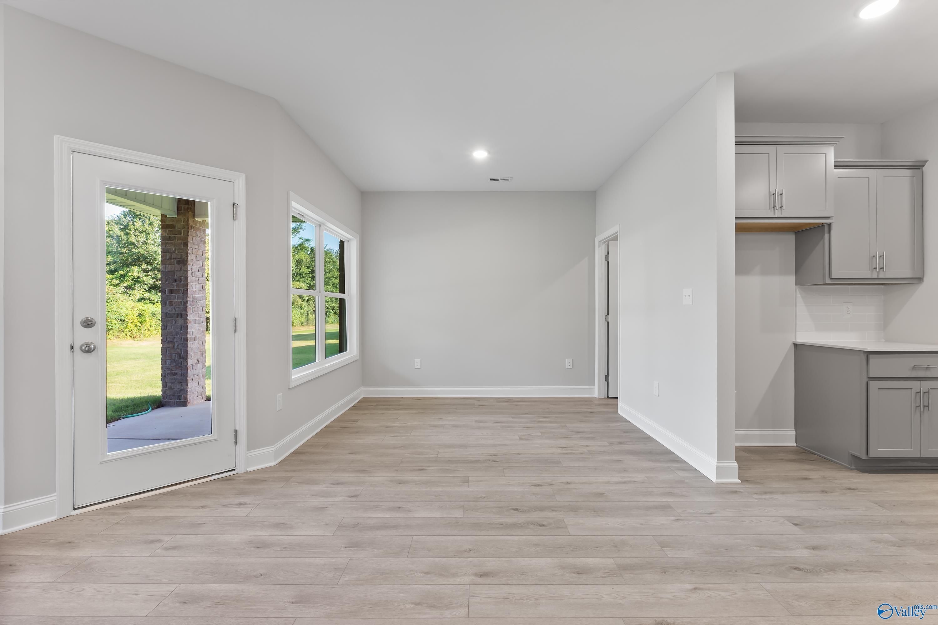 Spacious open hallway with hardwood floors, back door to wooded yard, and adjacent kitchen in The Daphne C 4-bedroom home, Huntsville, AL