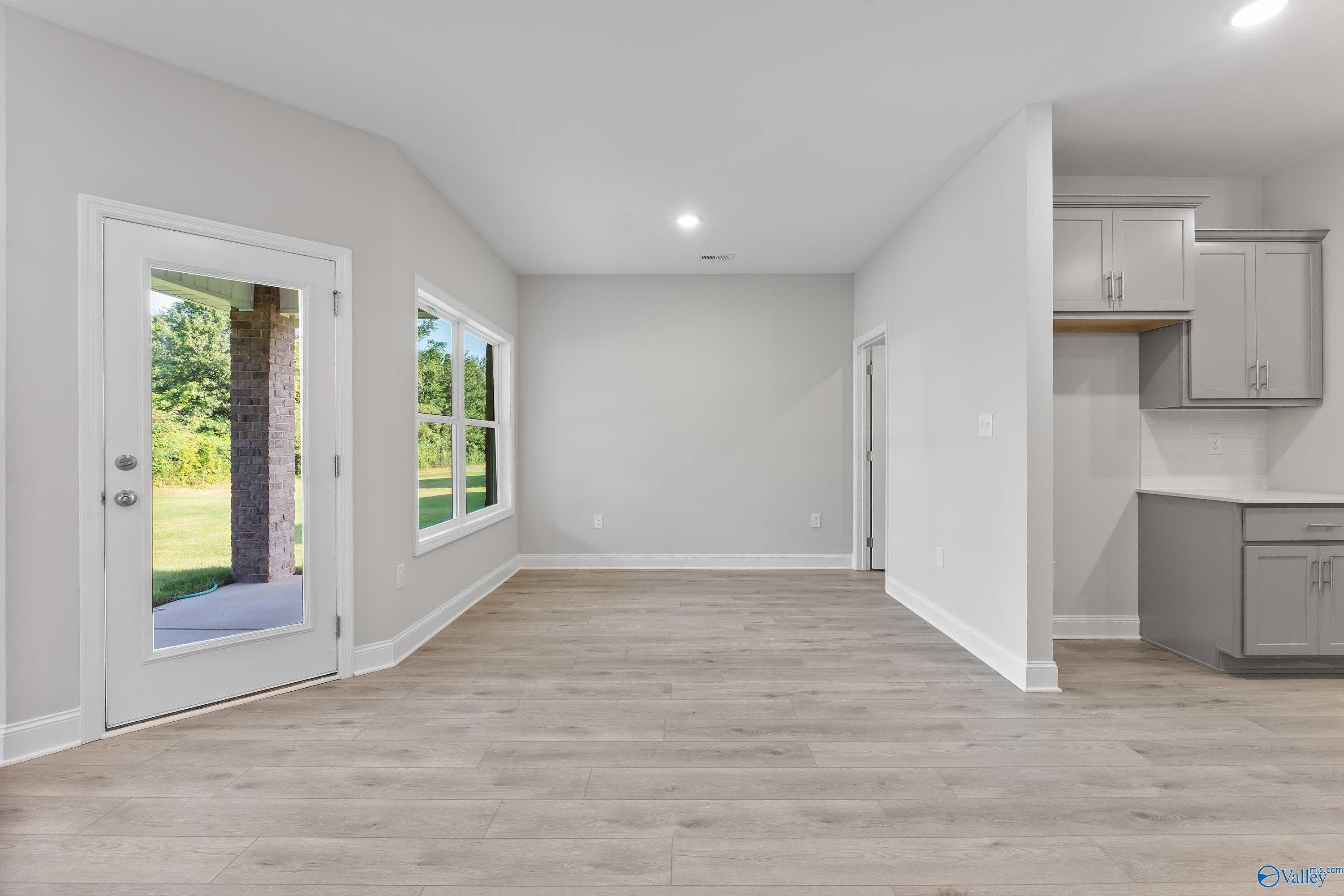 Spacious open hallway with hardwood floors, back door to wooded yard, and adjacent kitchen in The Daphne C 4-bedroom home, Huntsville, AL