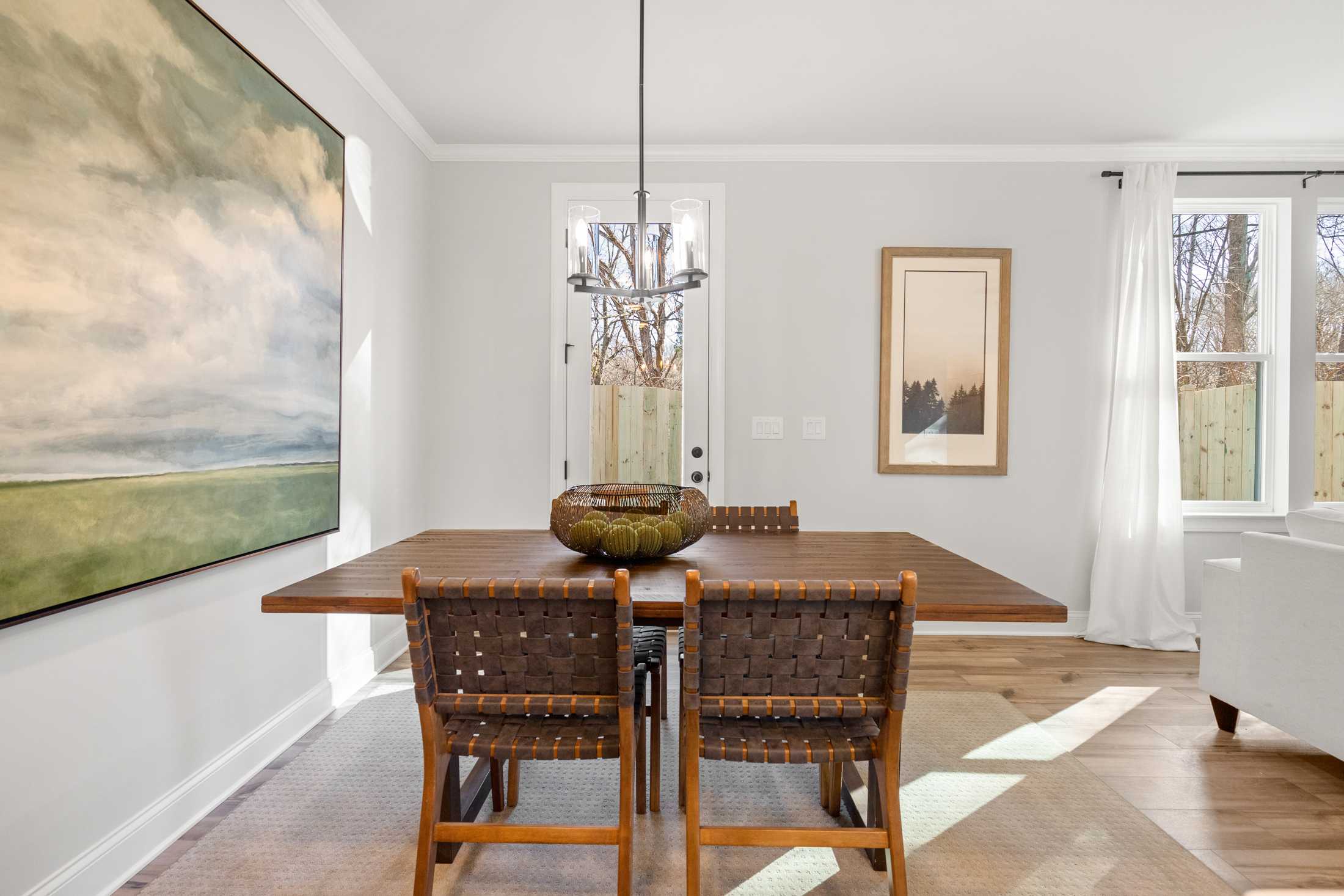 Elegant dining room at Rosehill Townhomes in Marietta, Georgia with wooden table, rattan chairs, chandelier, and abstract wall art