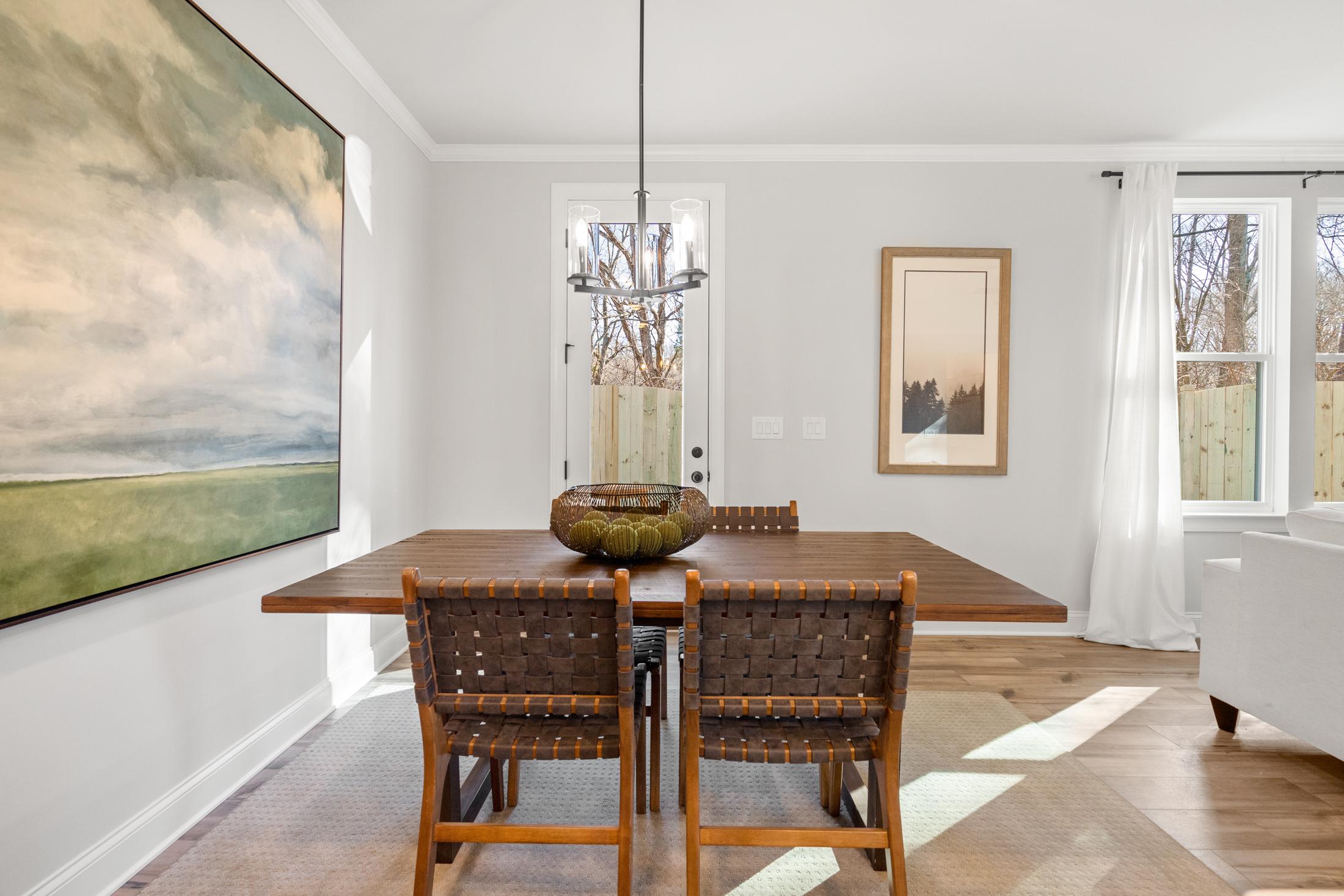 Elegant dining room at Rosehill Townhomes in Marietta, Georgia with wooden table, rattan chairs, chandelier, and abstract wall art
