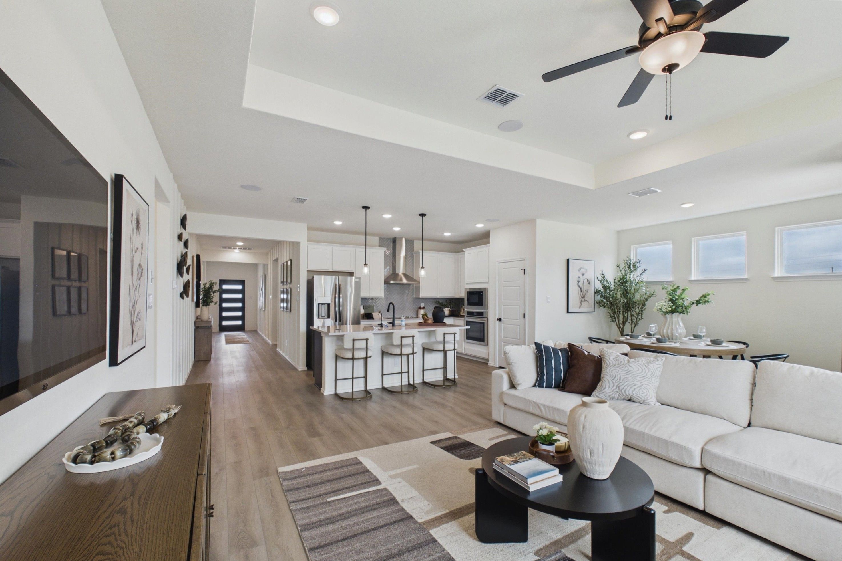 Open-concept kitchen and living room in Rayburn Valley San Antonio TX home with white island, hardwood floors, orange sofa, ceiling fan