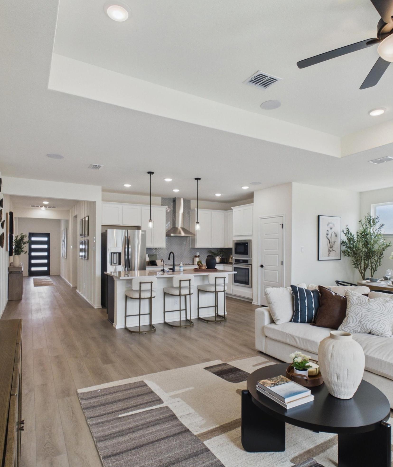 Open-concept kitchen and living room in Rayburn Valley San Antonio TX home with white island, hardwood floors, orange sofa, ceiling fan