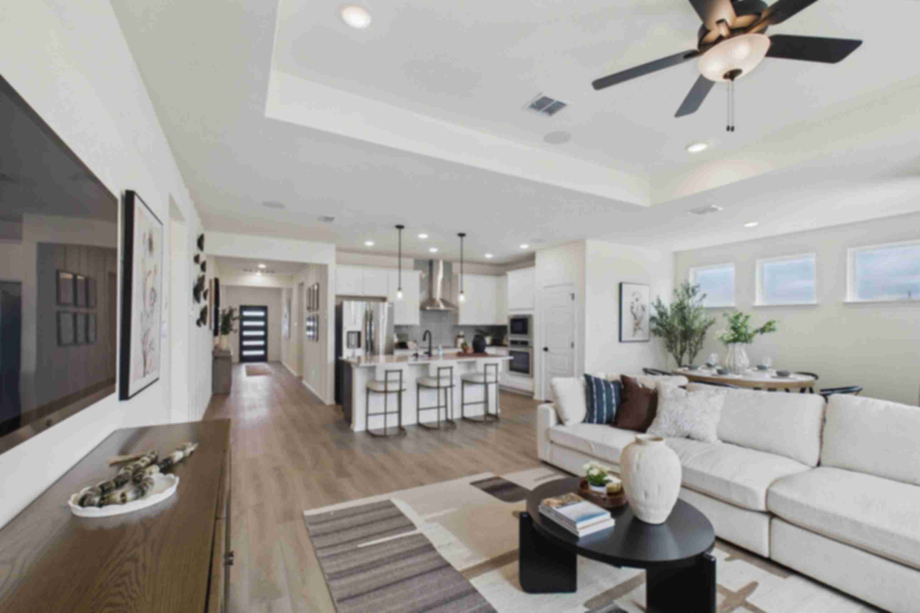 Open-concept kitchen and living room in Rayburn Valley San Antonio TX home with white island, hardwood floors, orange sofa, ceiling fan