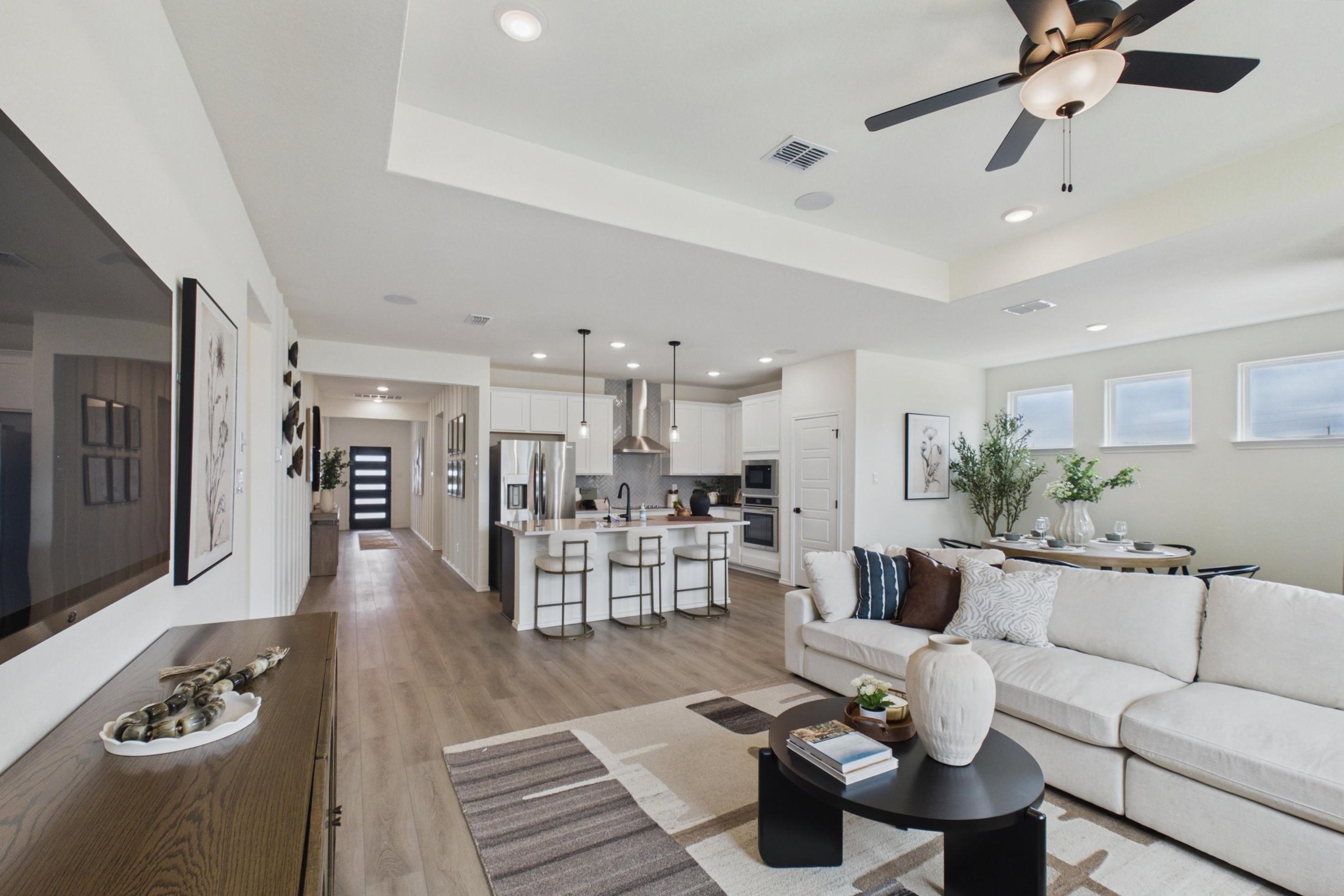 Open-concept kitchen and living room in Rayburn Valley San Antonio TX home with white island, hardwood floors, orange sofa, ceiling fan
