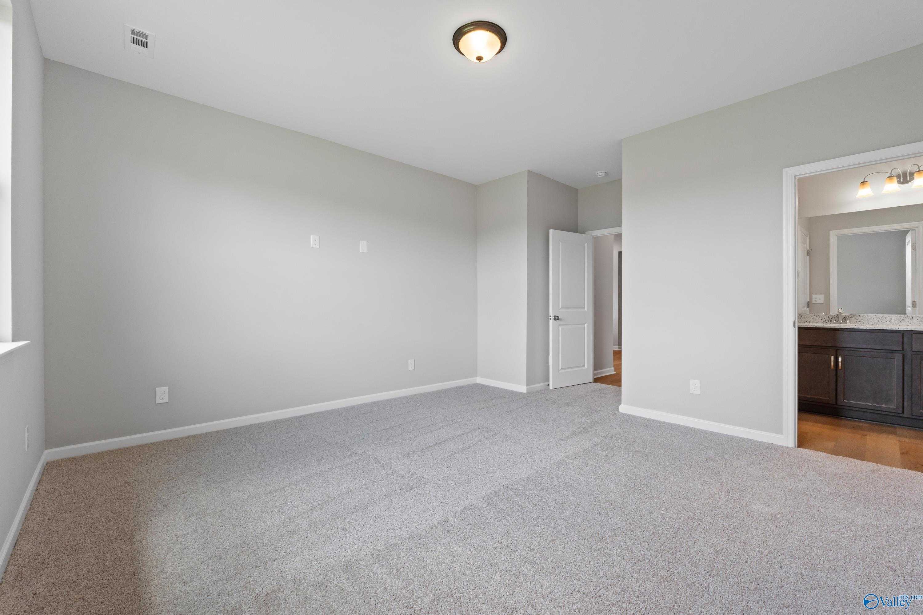 Spacious secondary bedroom with gray walls, carpet flooring, and en-suite bath with double vanity in Evermore Homes The Aurora, Harvest, AL