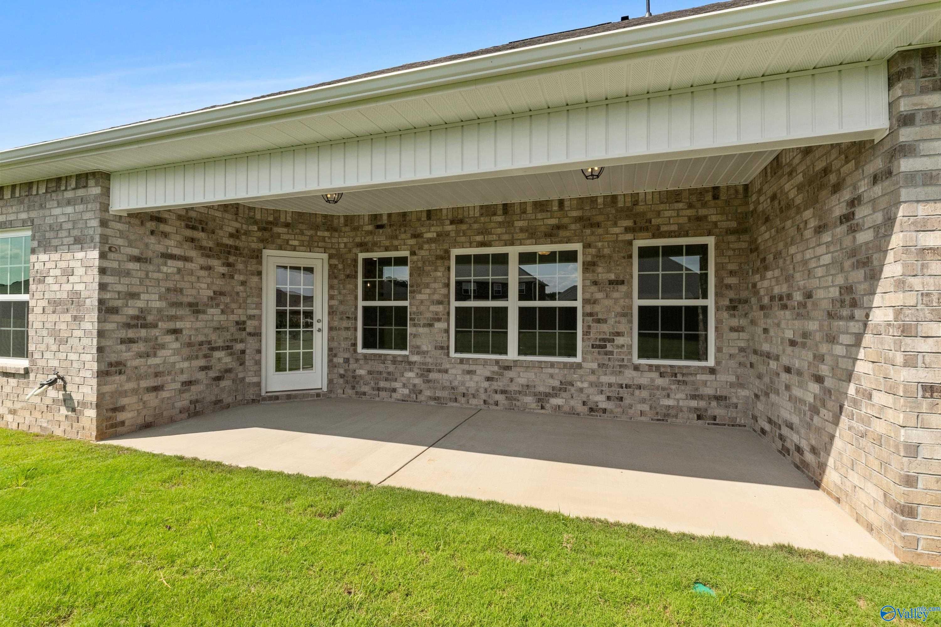 Covered patio with French doors and windows on brick exterior of 3-bedroom Davidson Homes Rockford B in Toney, Alabama