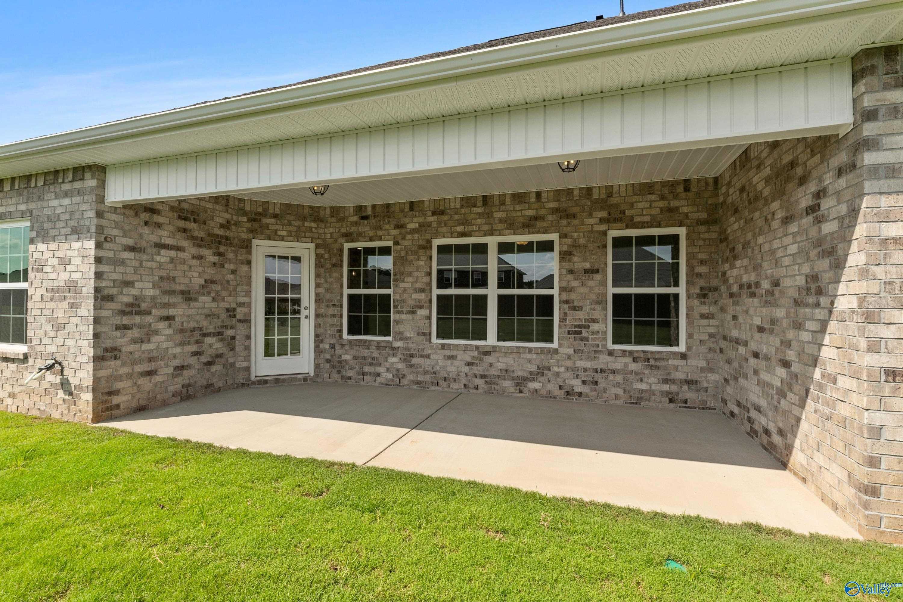 Covered patio with French doors and windows on brick exterior of 3-bedroom Davidson Homes Rockford B in Toney, Alabama