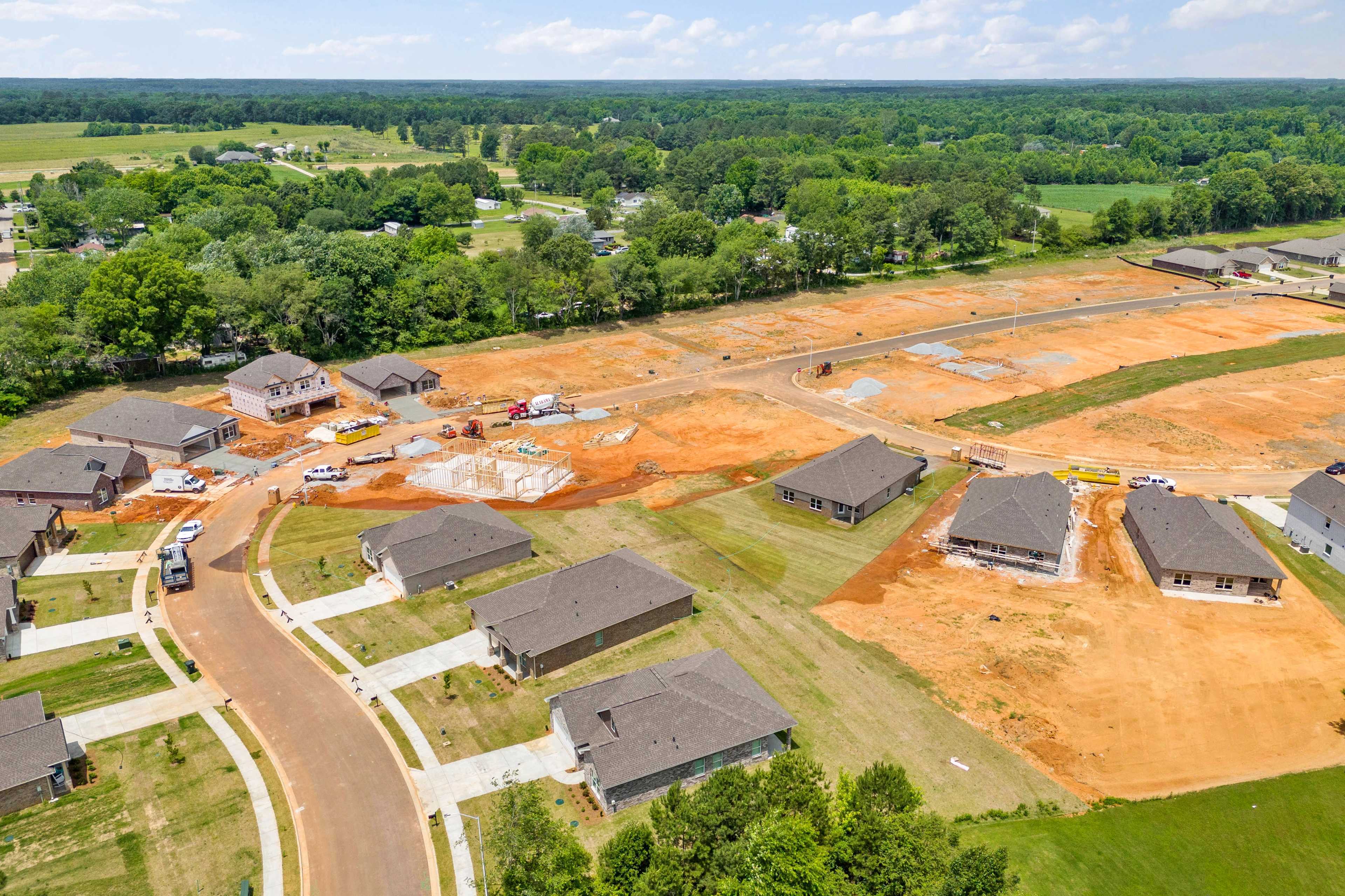 Aerial view of new home construction at Durham Farms in Harvest Alabama featuring framed houses dirt lots and wooded fields