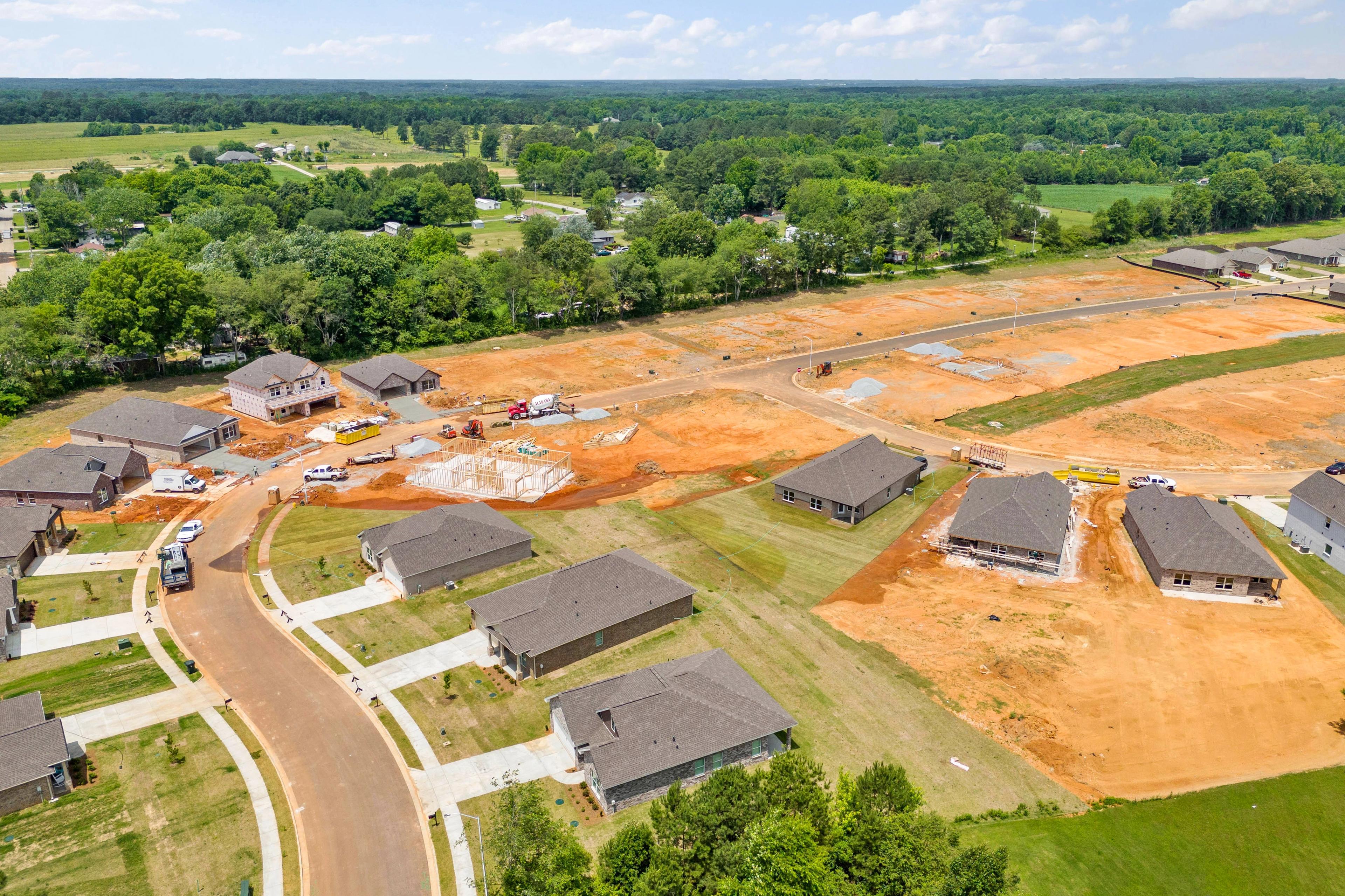 Aerial view of new home construction at Durham Farms in Harvest Alabama featuring framed houses dirt lots and wooded fields