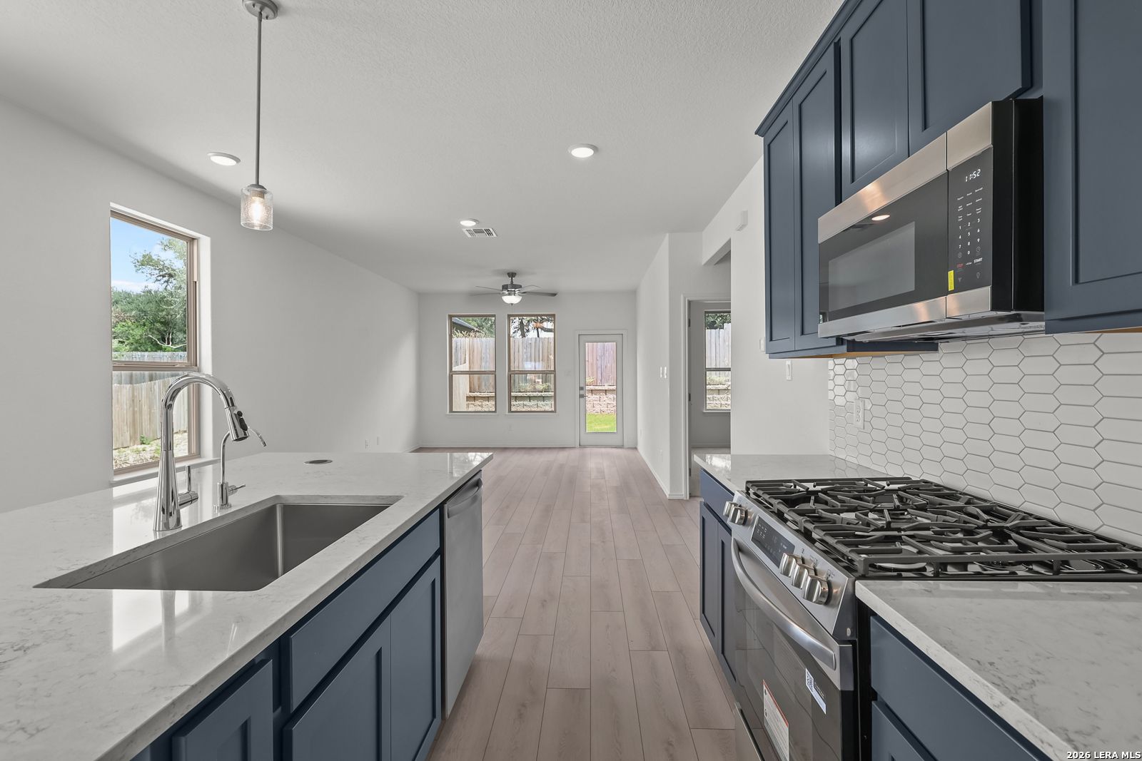 Modern kitchen with navy cabinets, quartz countertops, and gas range in The Gillian C home, Meadows at Oak Creek, San Antonio.