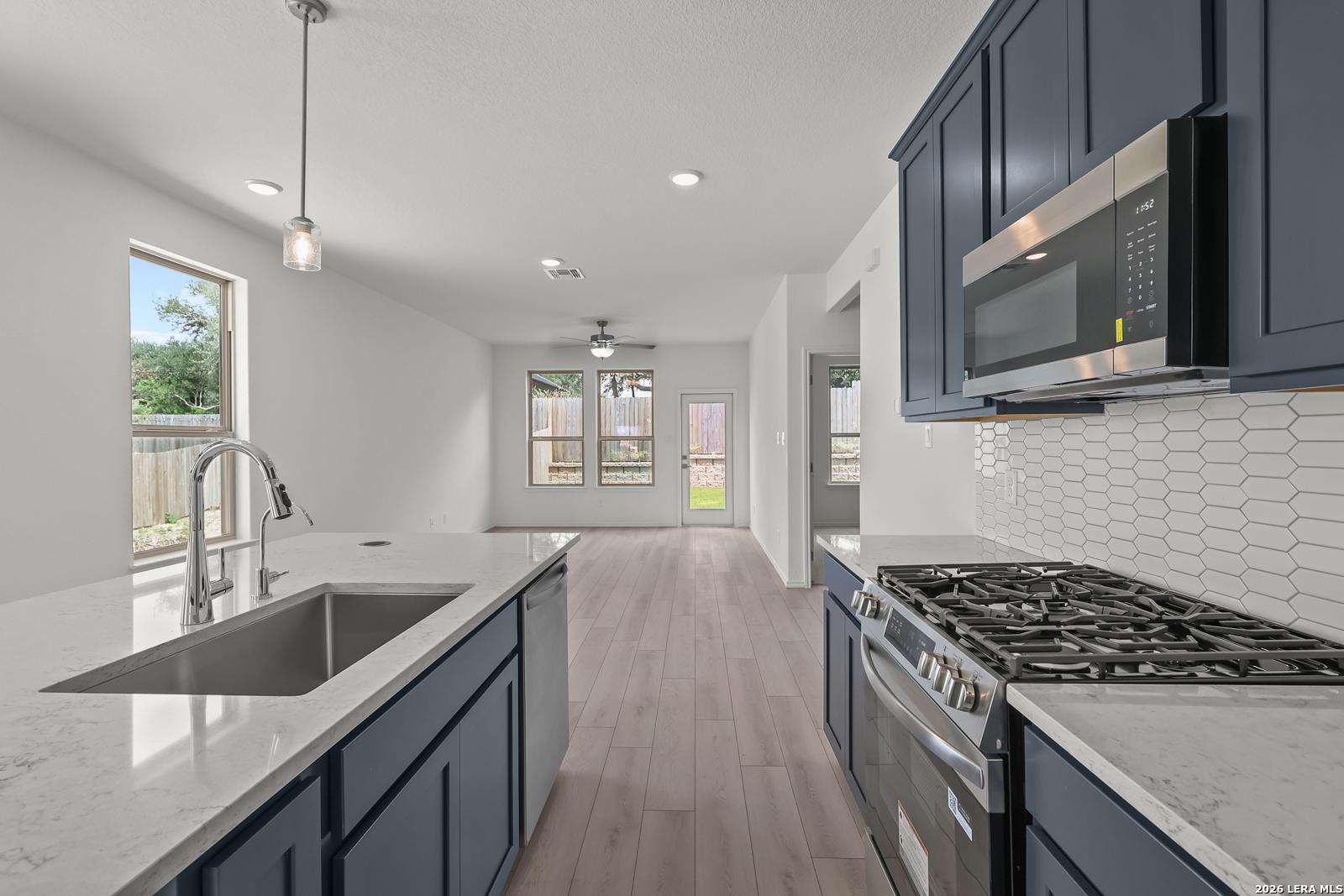 Modern kitchen with navy cabinets, quartz countertops, and gas range in The Gillian C home, Meadows at Oak Creek, San Antonio.