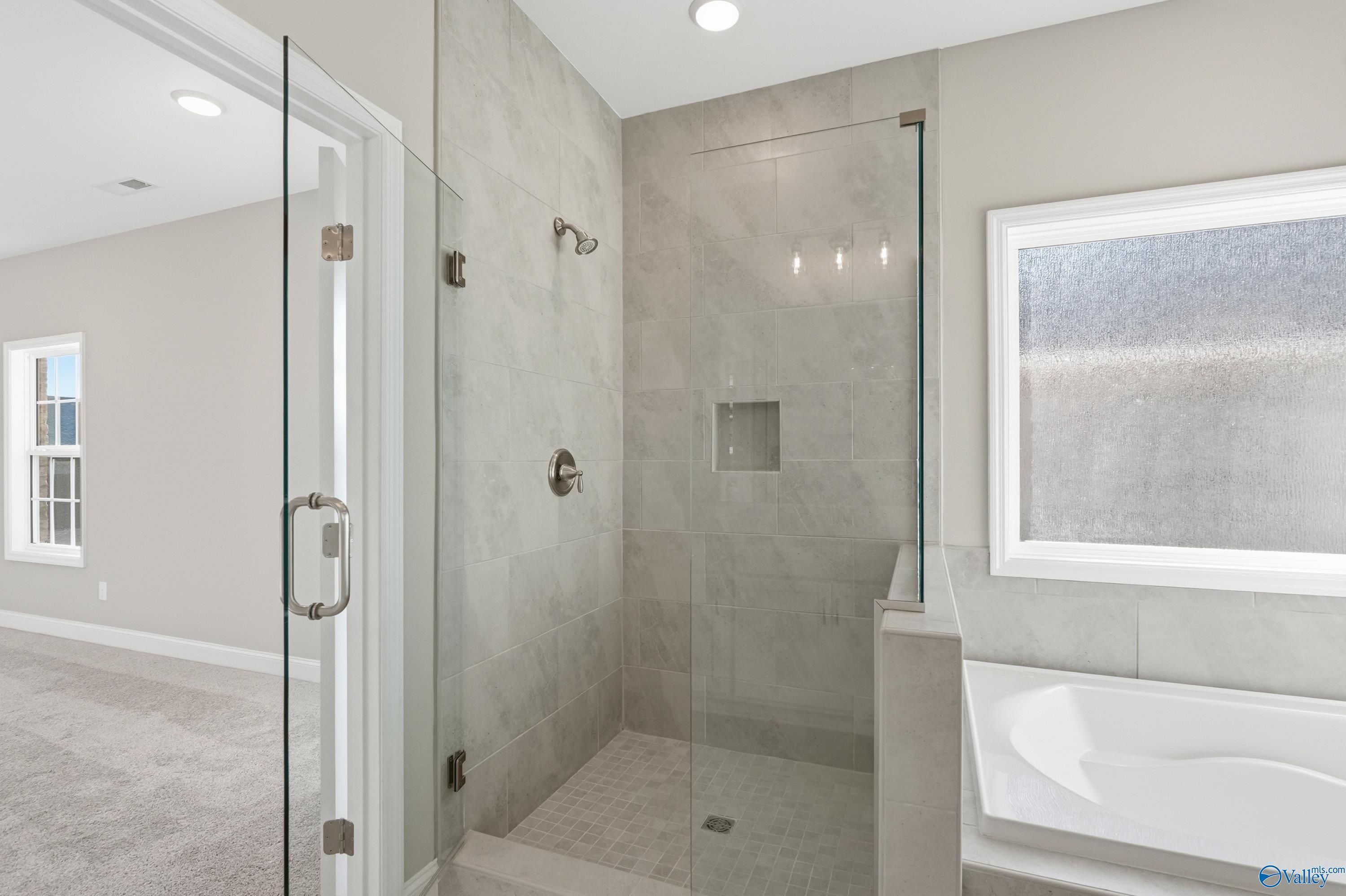 Modern master bathroom featuring frameless glass shower and freestanding tub in Davidson Homes The Lanier, Toney, Alabama
