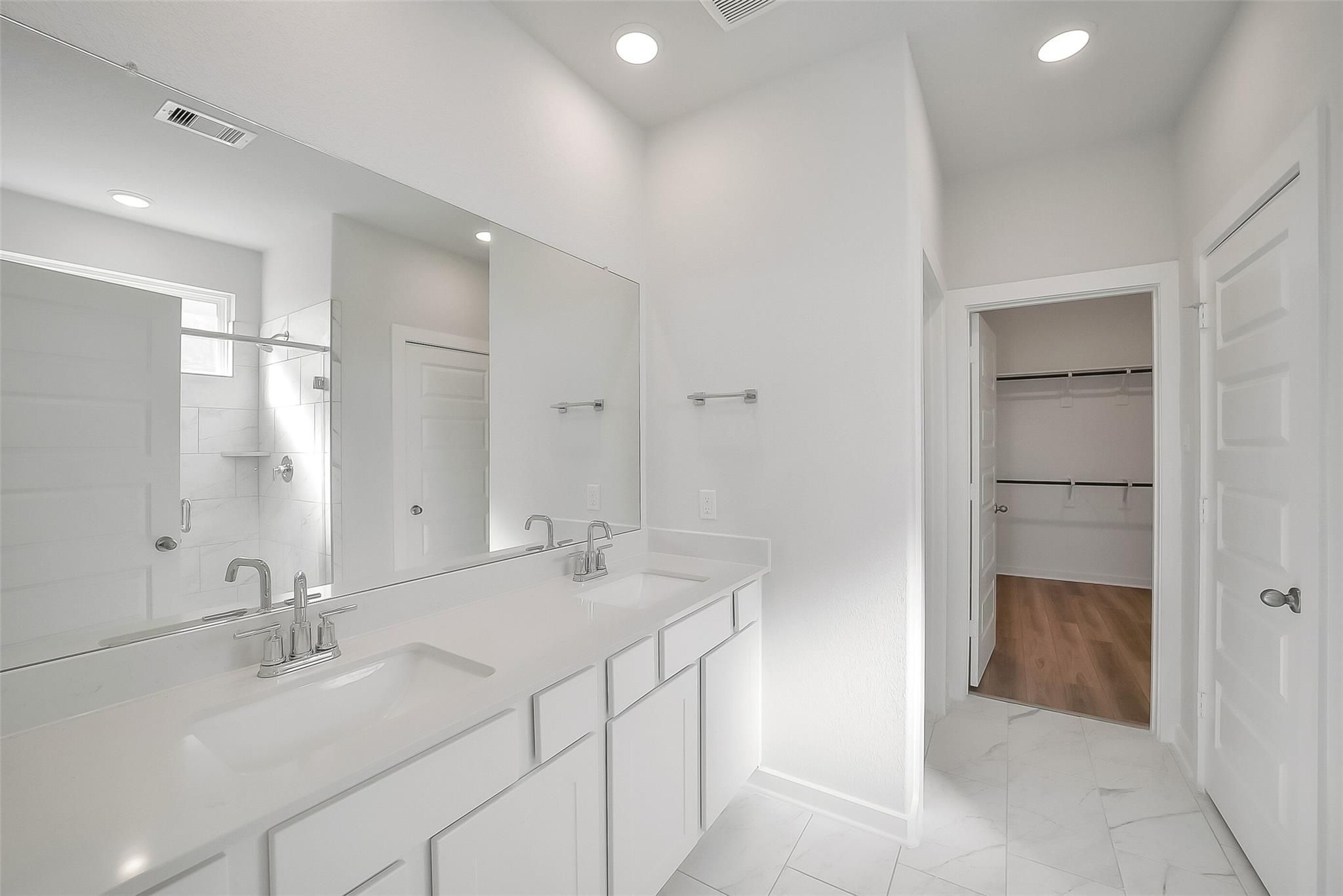 Spacious master bathroom featuring double vanity, walk-in shower, and closet in Davidson Homes The Acadia A, Sunterra, Katy, Texas