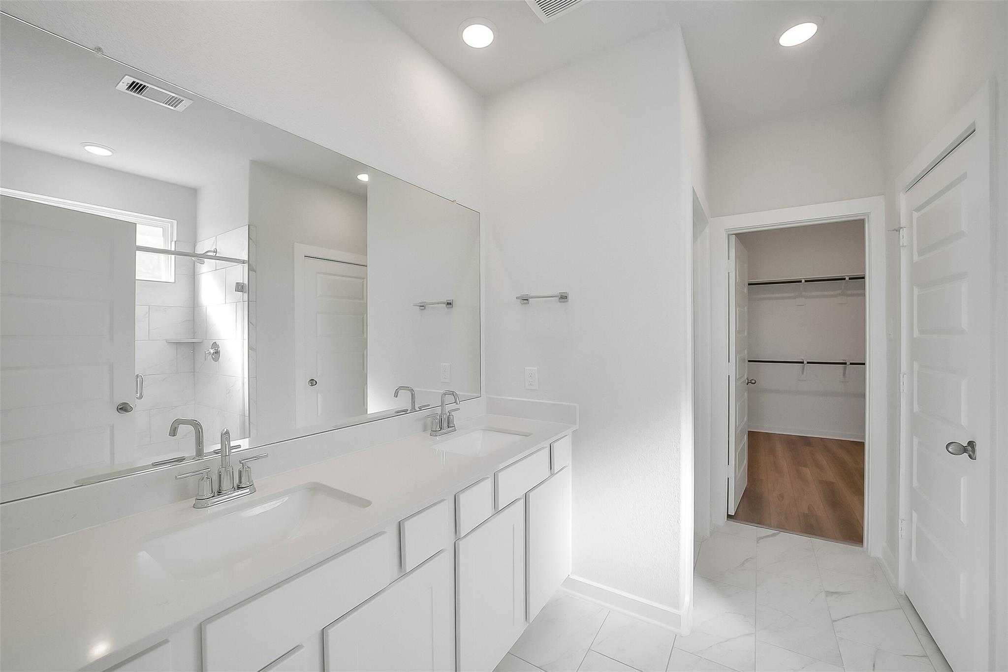 Spacious master bathroom featuring double vanity, walk-in shower, and closet in Davidson Homes The Acadia A, Sunterra, Katy, Texas