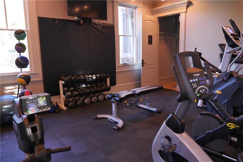Spacious home gym with treadmill, elliptical, weights rack, bench, and TV in Davidson Homes Seaside B, Woodstock, Georgia