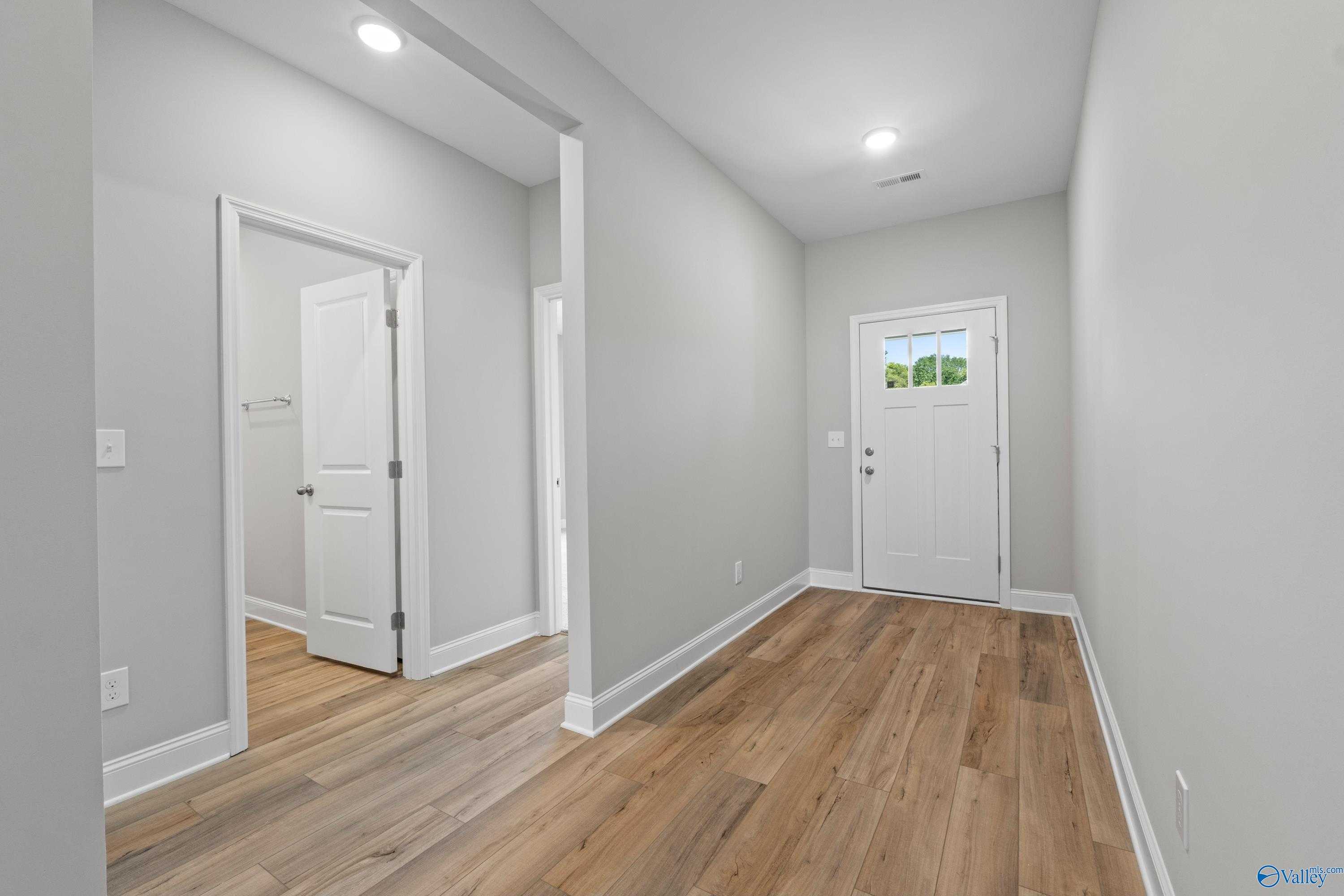 Bright entry foyer with hardwood floors, gray walls, and white doors in 4-bedroom The Daphne C home, The Meadows, Athens Alabama