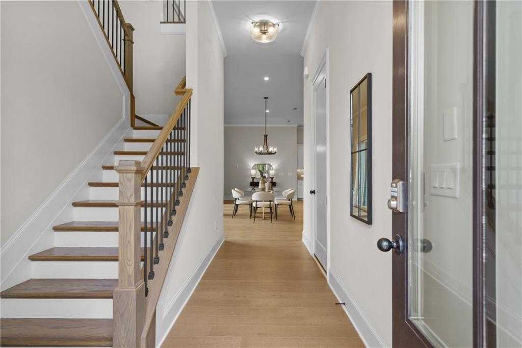 Elegant hallway with oak hardwood floors, wrought iron staircase, and formal dining room chandelier in Davidson Homes The Seaside B, Woodstock, Georgia