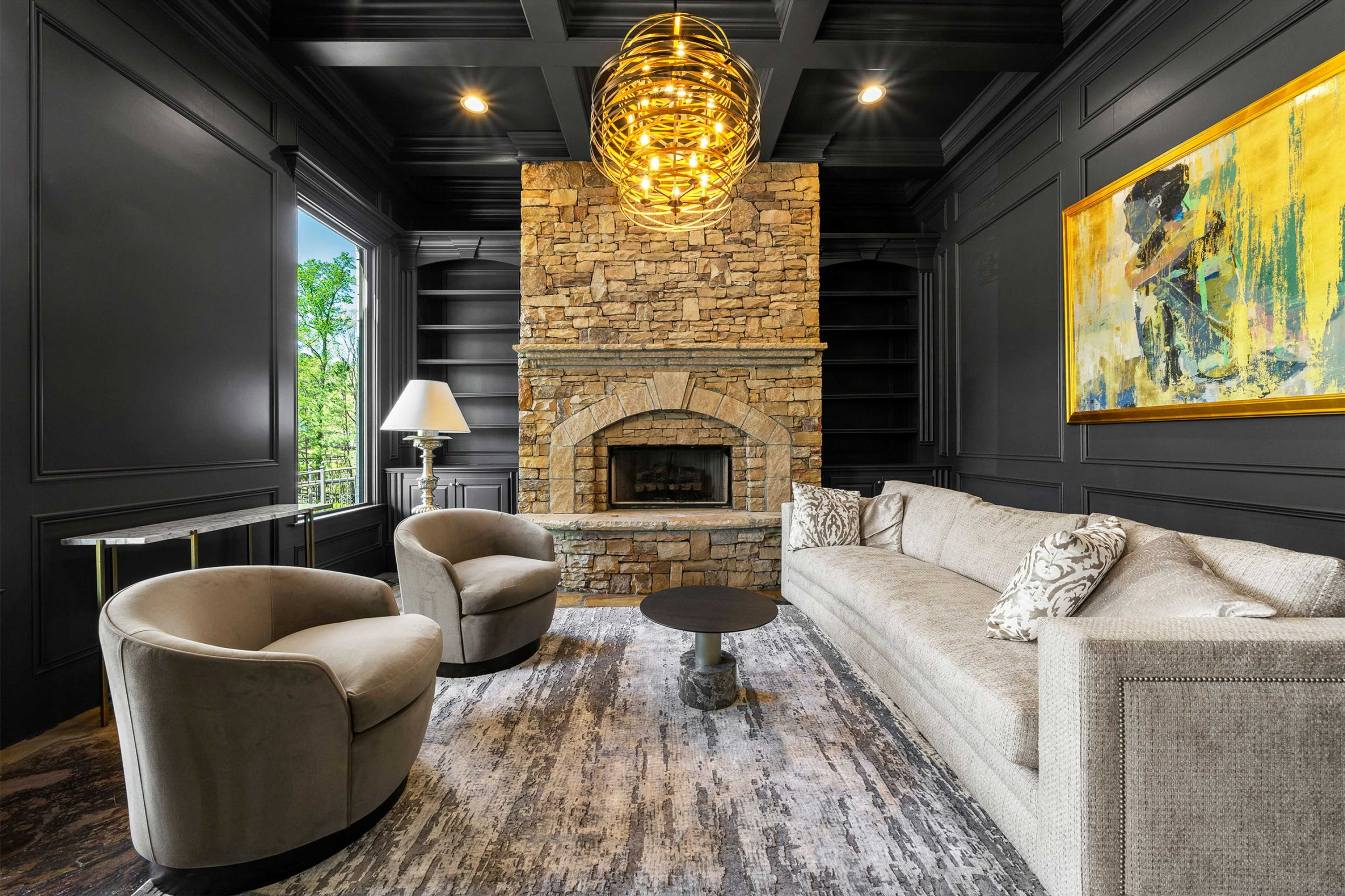 Elegant study with stone fireplace, dark paneled walls, yellow chandelier, and plush seating at Riverwood in Dallas, Georgia