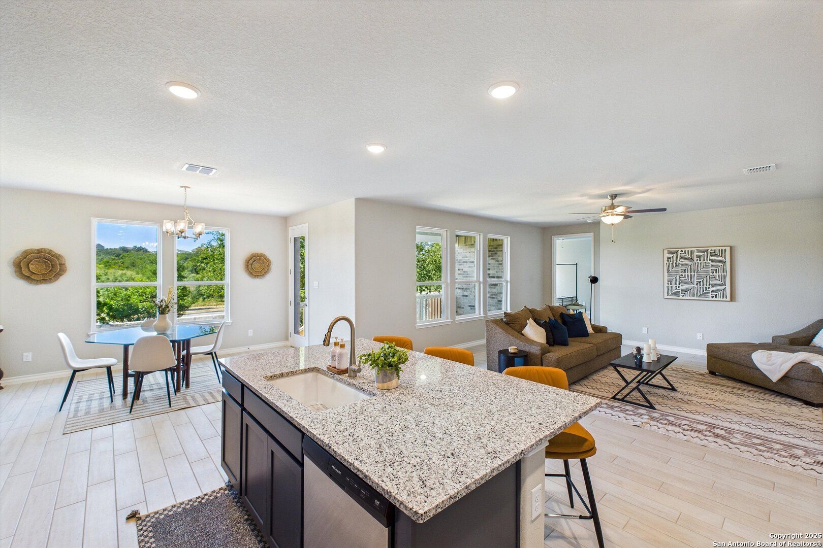 Open-concept kitchen with granite island, dining table, and cozy living area in The Jennings H by Davidson Homes, Ladera, San Antonio