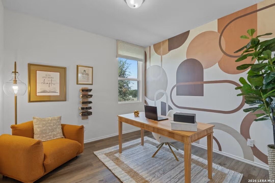 Modern home office with wooden desk, dual monitors, orange armchair, abstract geometric wall art, and potted plant in Davidson Homes The Daphne H, Seguin, Texas