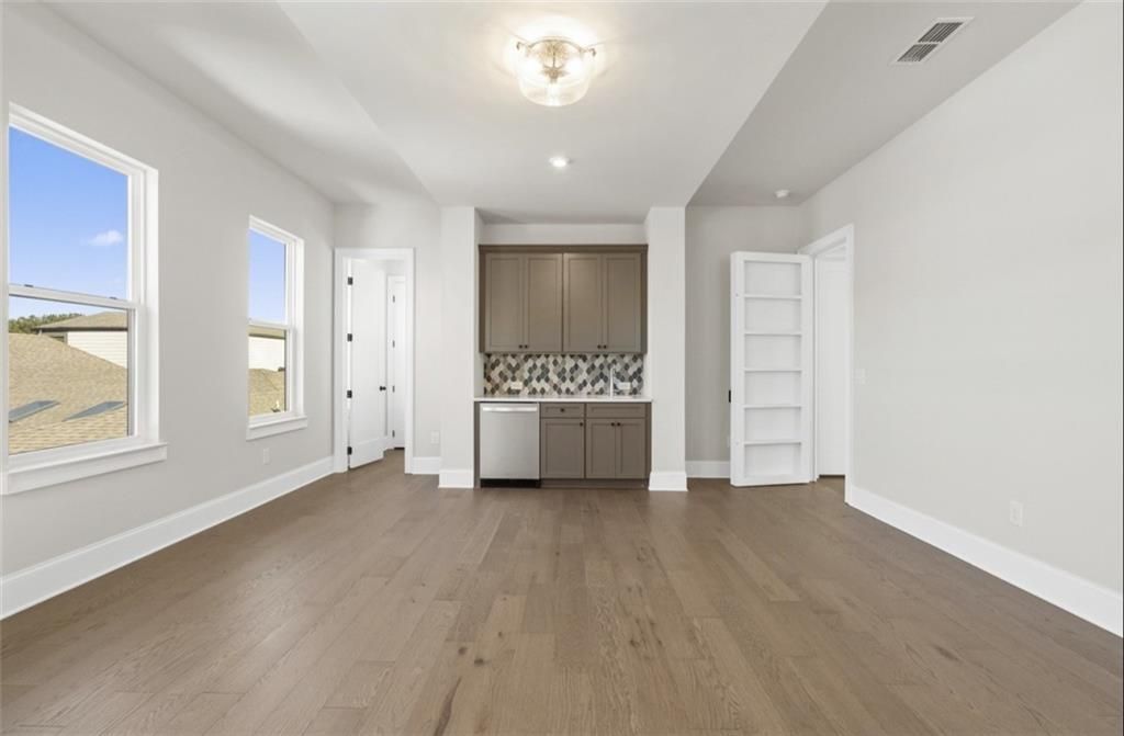 Bright open interior with hardwood floors, white walls, large windows, built-in wet bar and dishwasher in Davidson Homes The Seaside A, Woodstock, Georgia