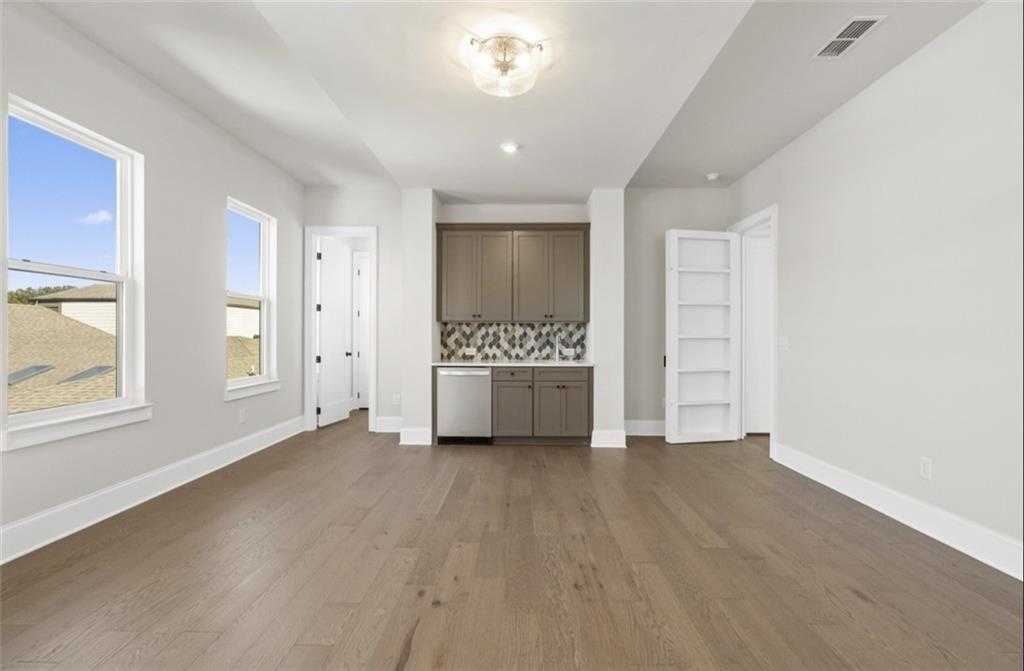 Bright open interior with hardwood floors, white walls, large windows, built-in wet bar and dishwasher in Davidson Homes The Seaside A, Woodstock, Georgia