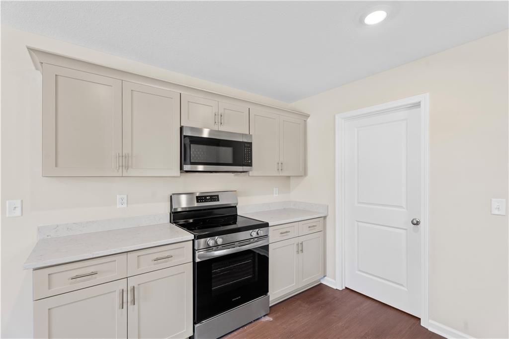 Modern kitchen with white shaker cabinets, stainless steel microwave and oven, quartz countertops in Davidson Homes The Washington, Phenix City