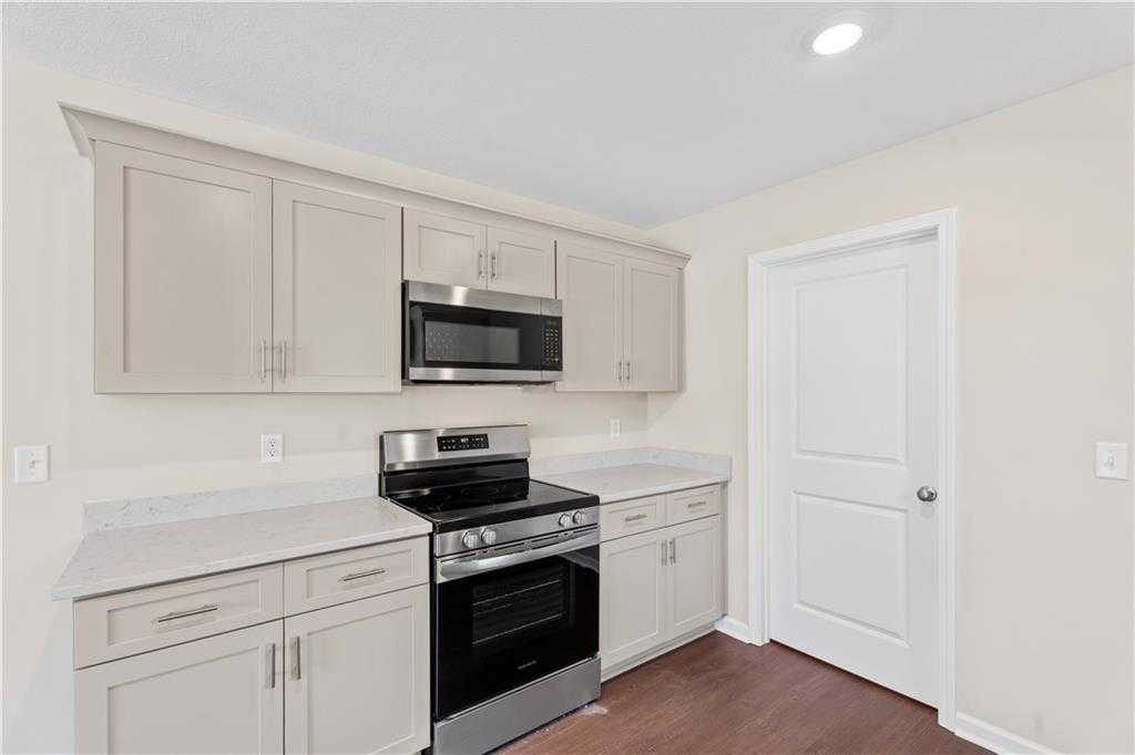 Modern kitchen with white shaker cabinets, stainless steel microwave and oven, quartz countertops in Davidson Homes The Washington, Phenix City