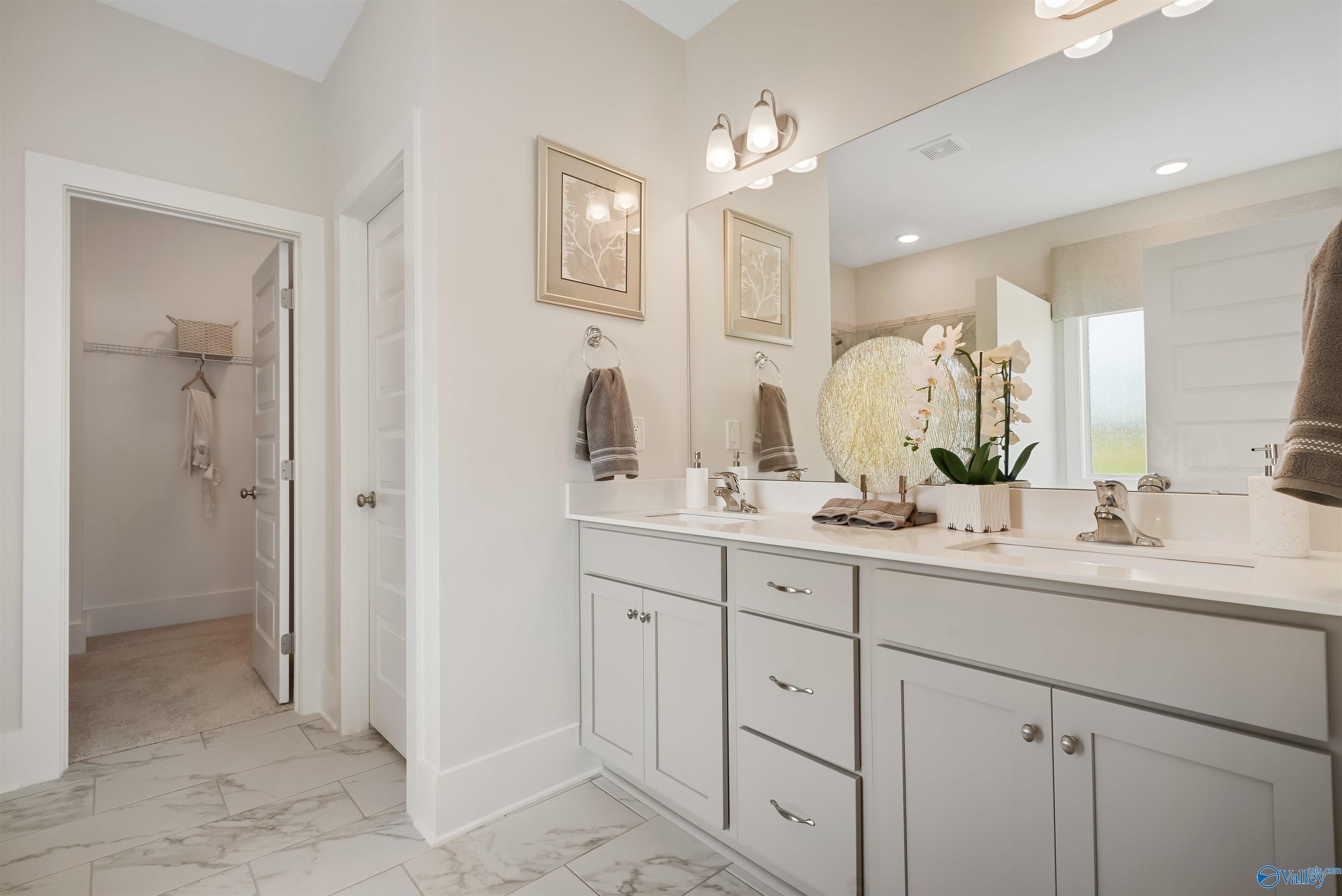 Elegant master bathroom with double vanity, white shaker cabinets, mirrors, and orchid in The Everett by Davidson Homes, New Market, AL