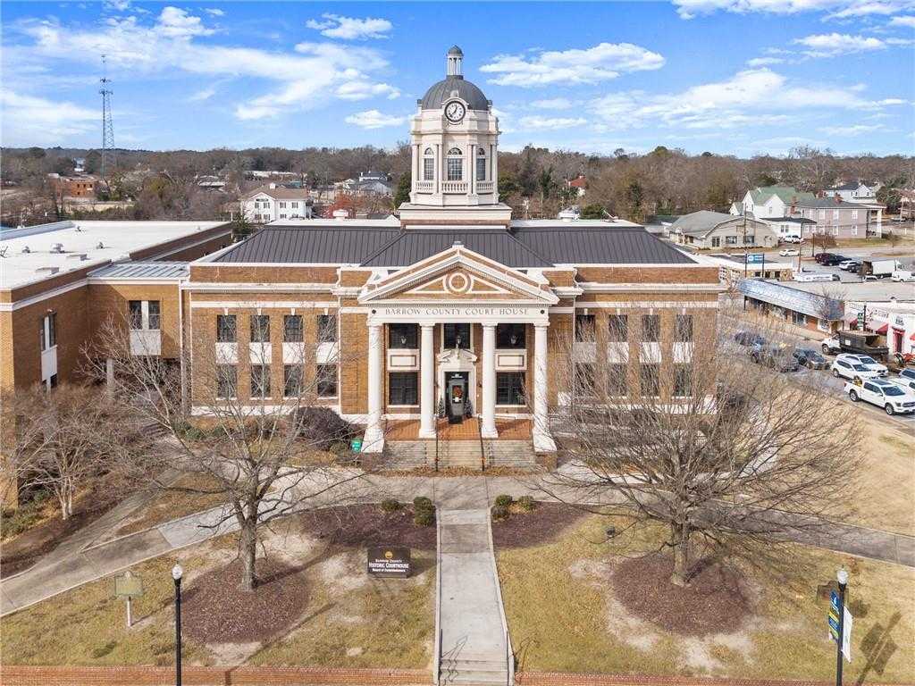 Historic red-brick courthouse with clock tower, columned entrance, and landscaped grounds in Winder, Georgia