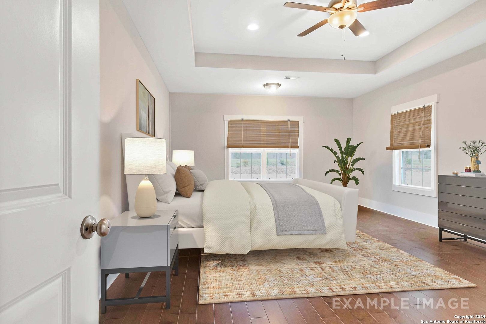 Cozy master bedroom with king bed, ceiling fan, bamboo blinds, and hardwood floors in Davidson Homes The Lanier H, Ladera San Antonio